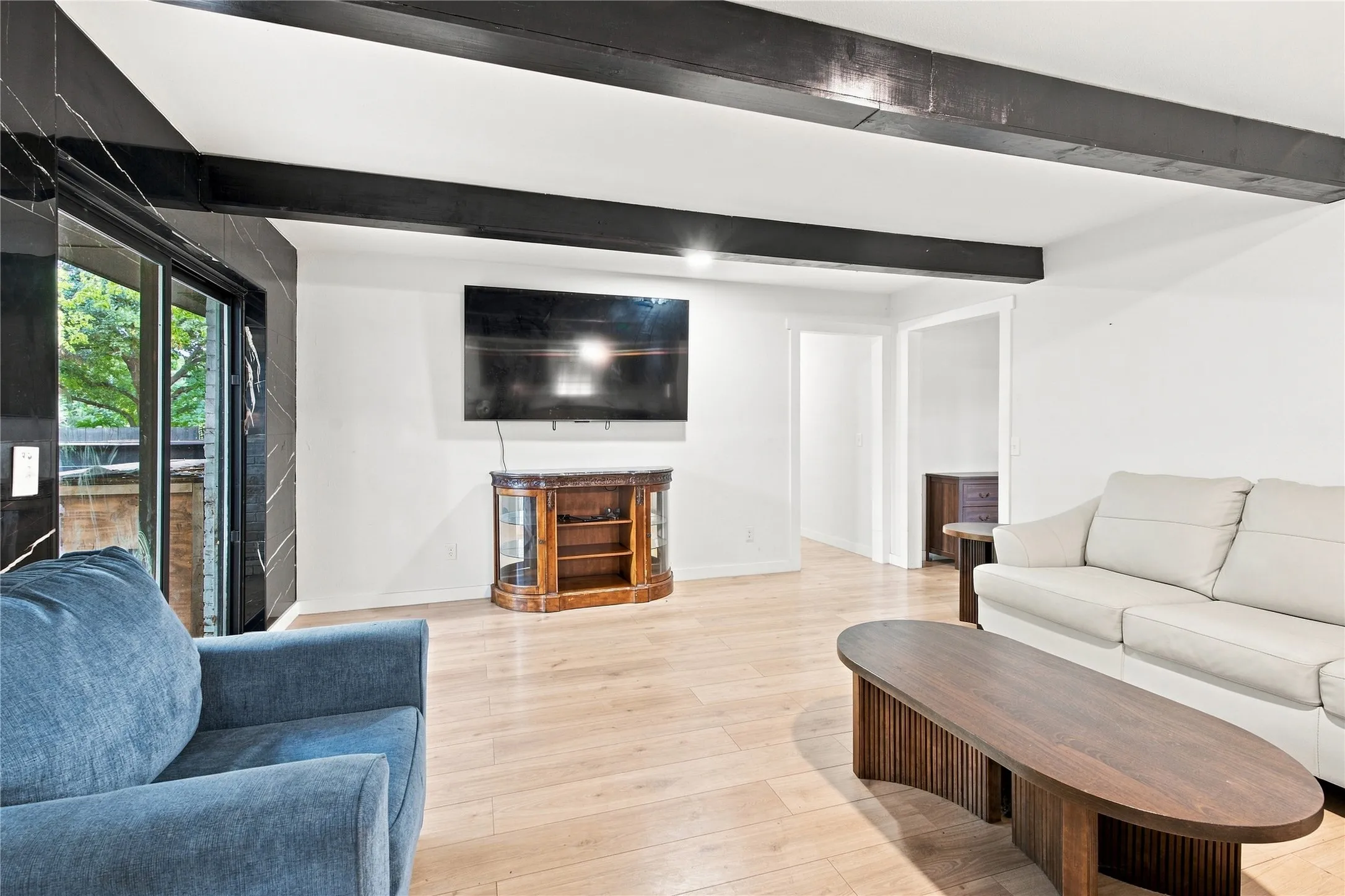 Recessed lighting, wood-finish flooring, exposed ceiling beams, and sliding glass doors