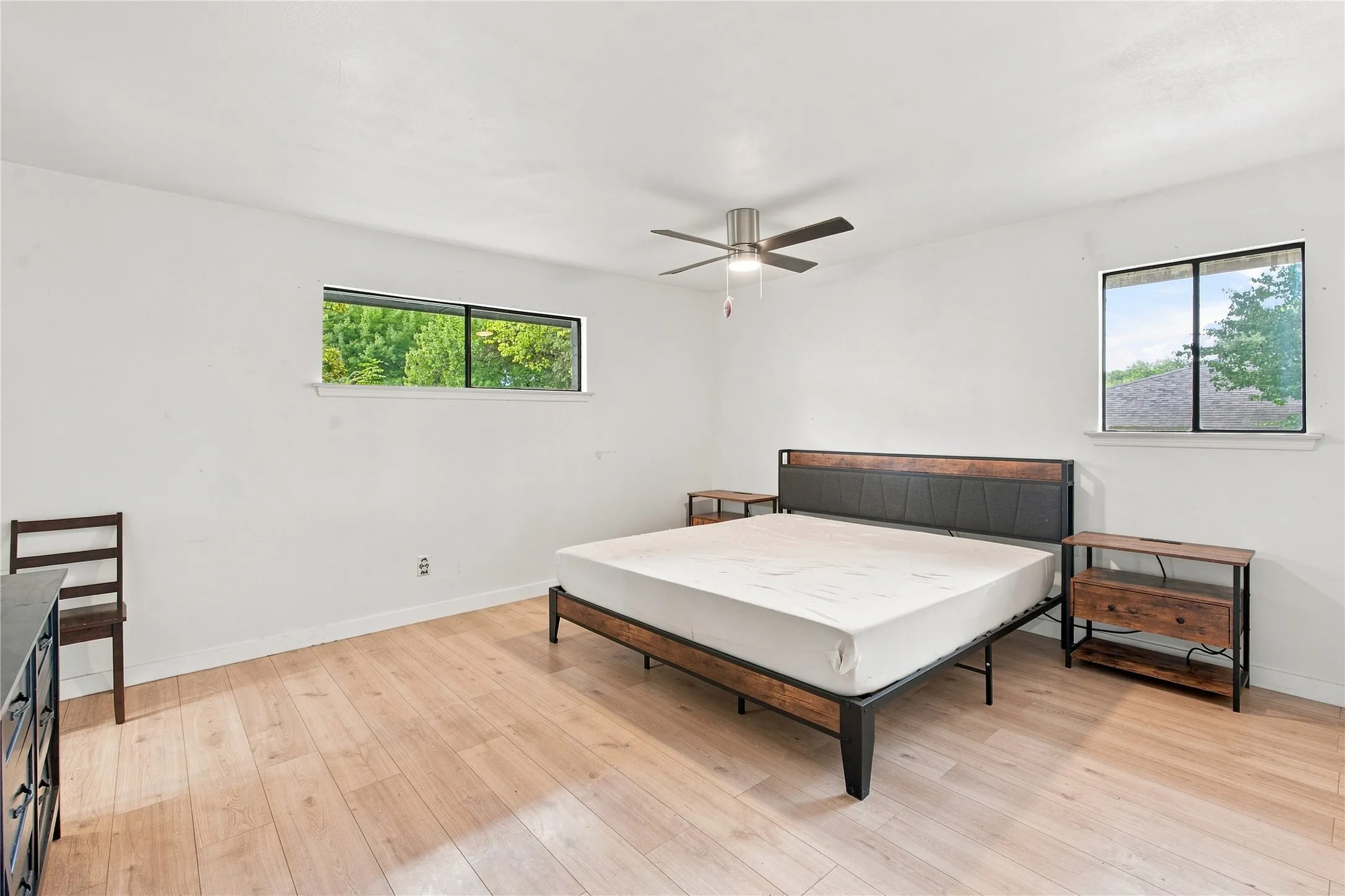 Light wood-finish flooring, white walls, and a ceiling fan with integrated lighting