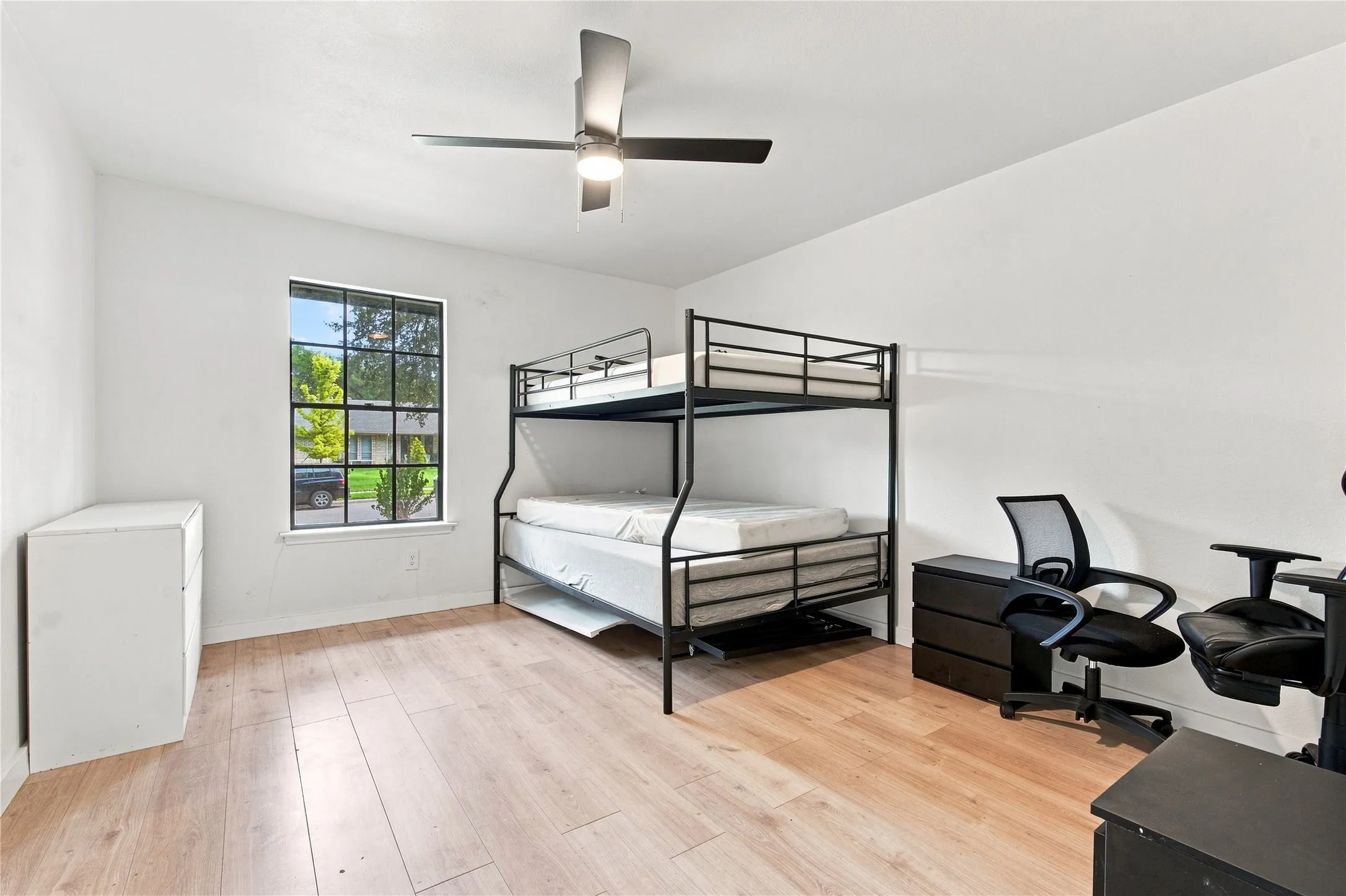 Light wood-finish flooring, white walls, and a multi-pane window