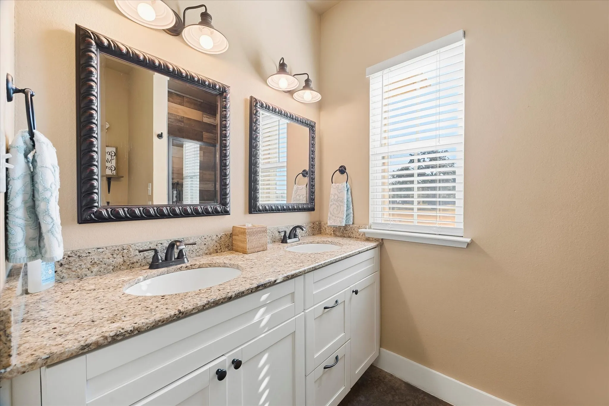 The front Hall Bath with dual sinks is shared by Bedrooms 2 and 3. The walk-in shower can be seen in the mirror's reflection.