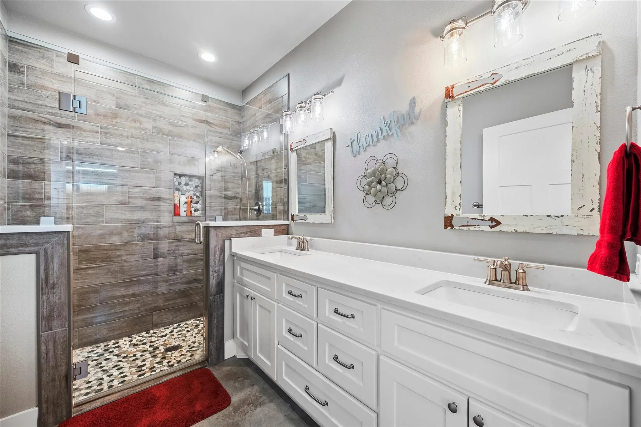 The bathroom offers dual sinks and accessible shower with a frameless glass enclosure.