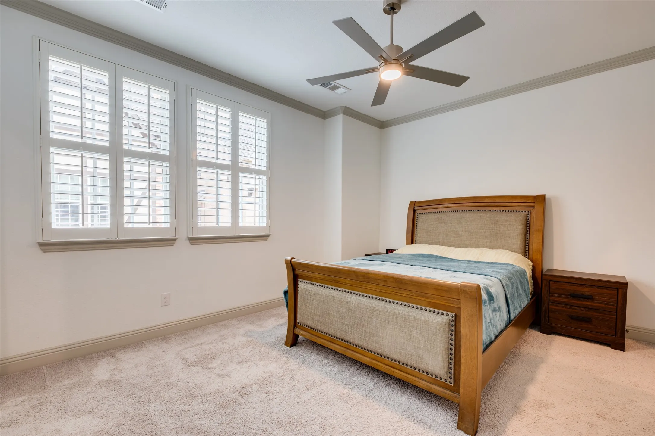 Large secondary bedroom with lots of natural lighting, ceiling fan and crown molding
