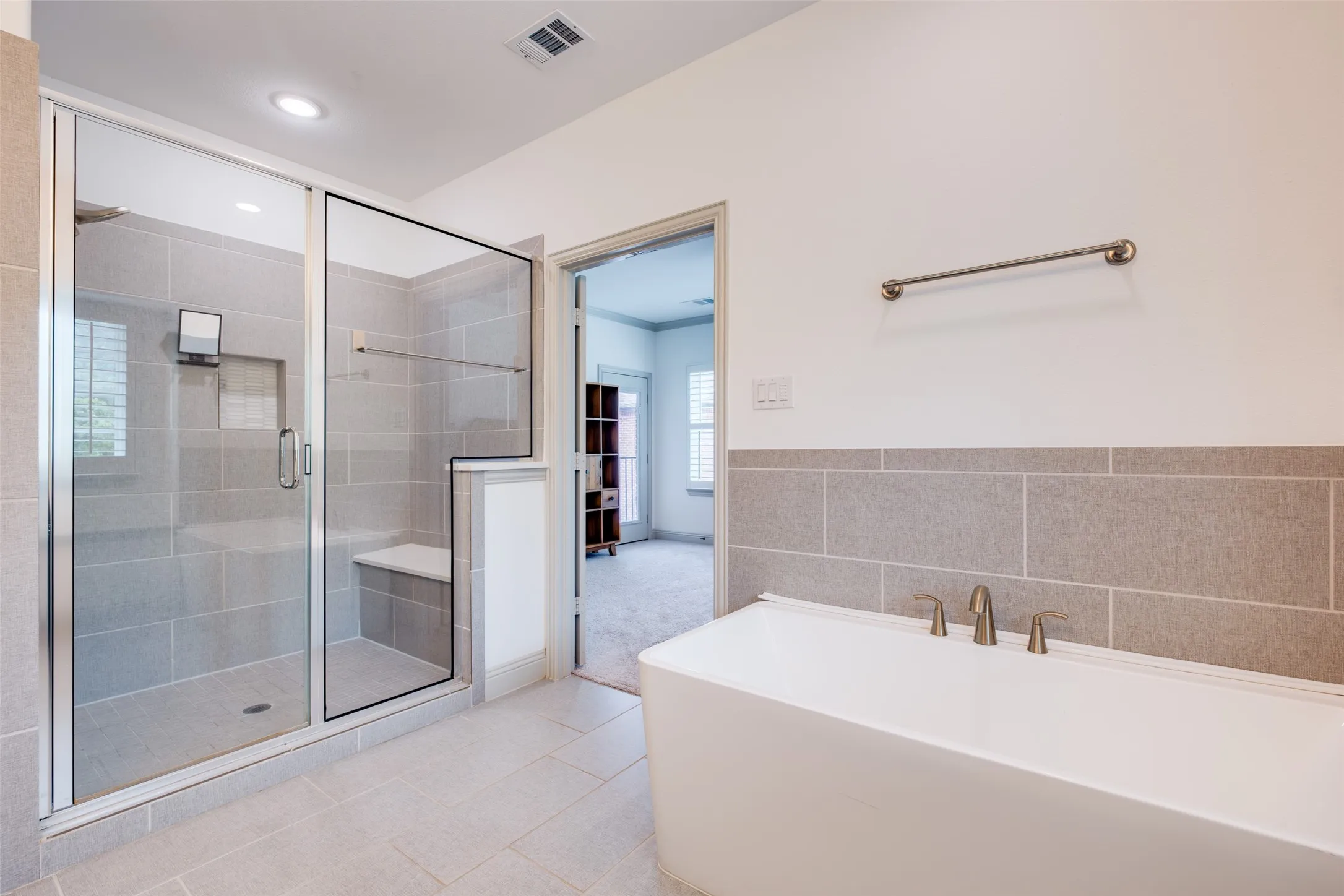 Ensuite primary bathroom with large shower with shower seat and separate soaker tub