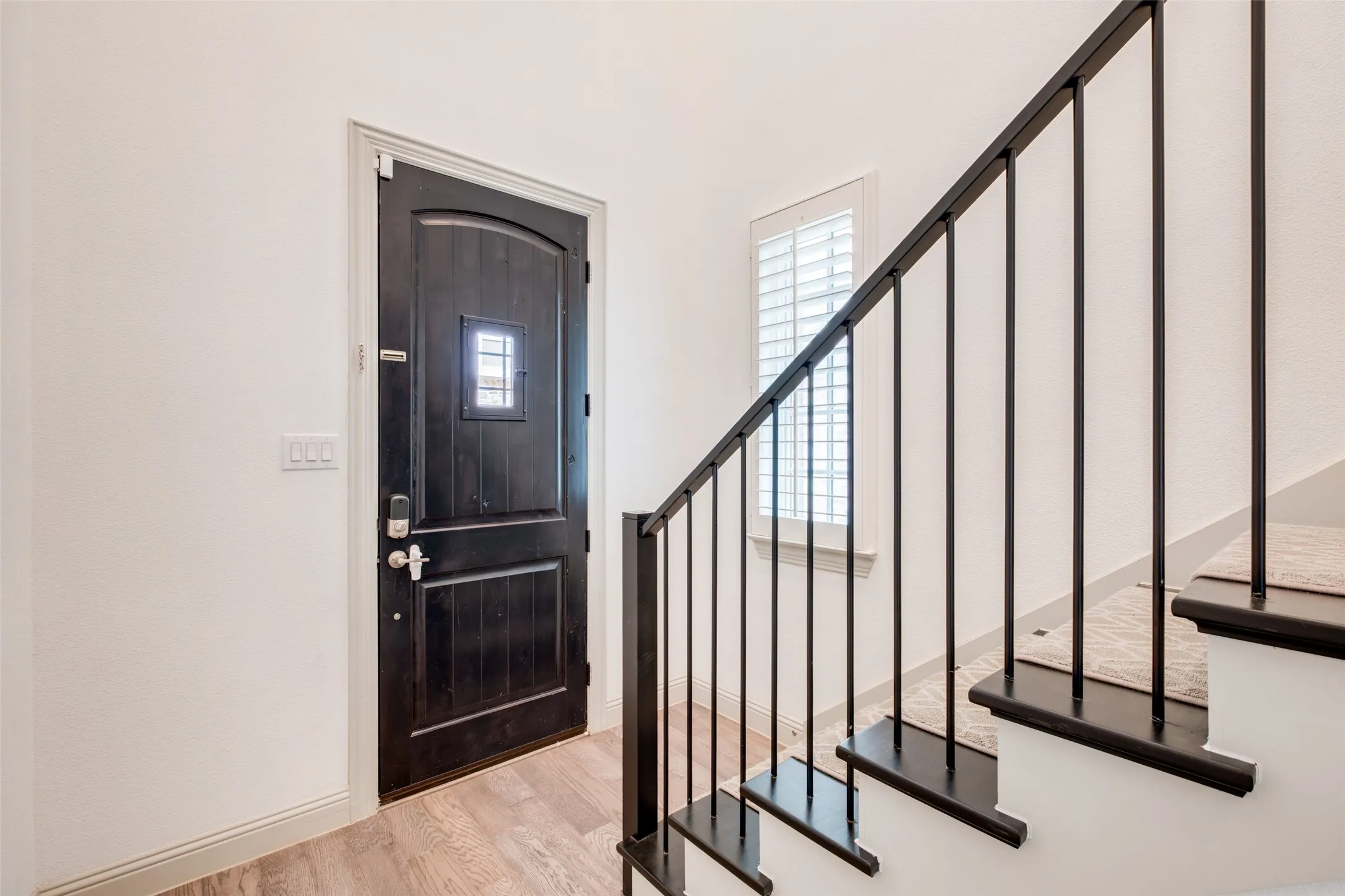 Entry with wood door, iron railing staircase and wood floors.