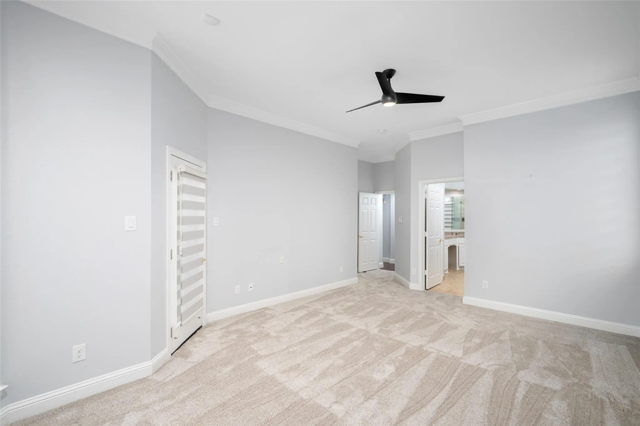 Spacious room with light gray wall paint, crown molding, and a contemporary ceiling fan