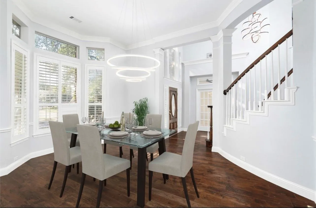 Dining area with wood-finish flooring, bay window with plantation shutters, contemporary chandelier, and columned archway