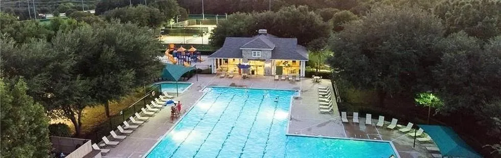 Expansive recreational area featuring a large swimming pool, a smaller wading pool, a dedicated pool house, a playground structure, and tennis courts
