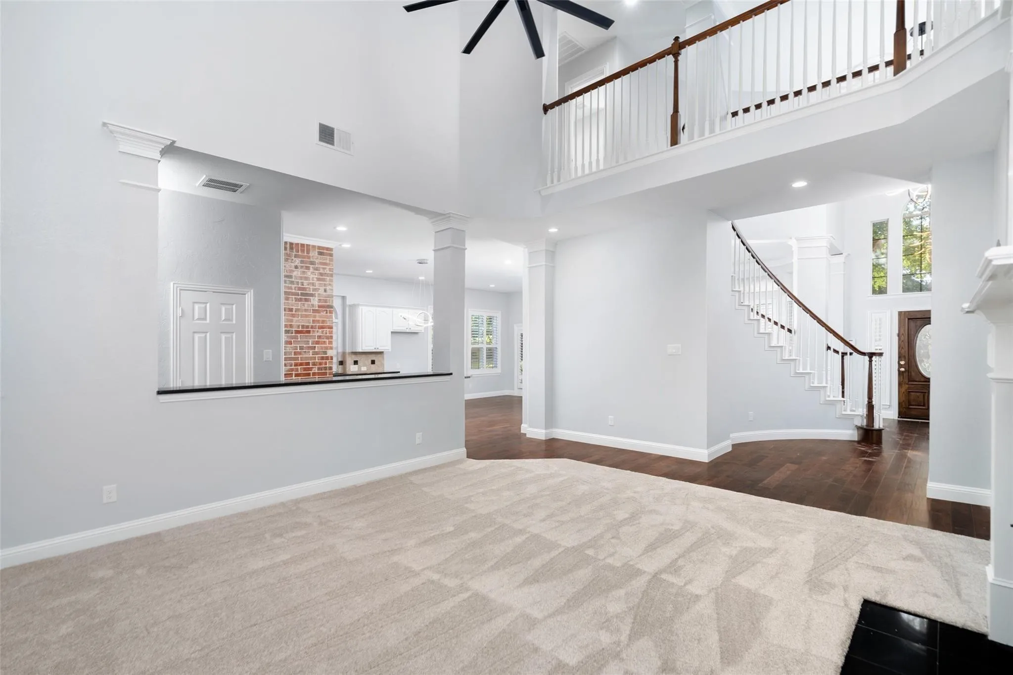 Two-story living area with high ceilings, a grand staircase, a second-story landing, and wood-finish flooring