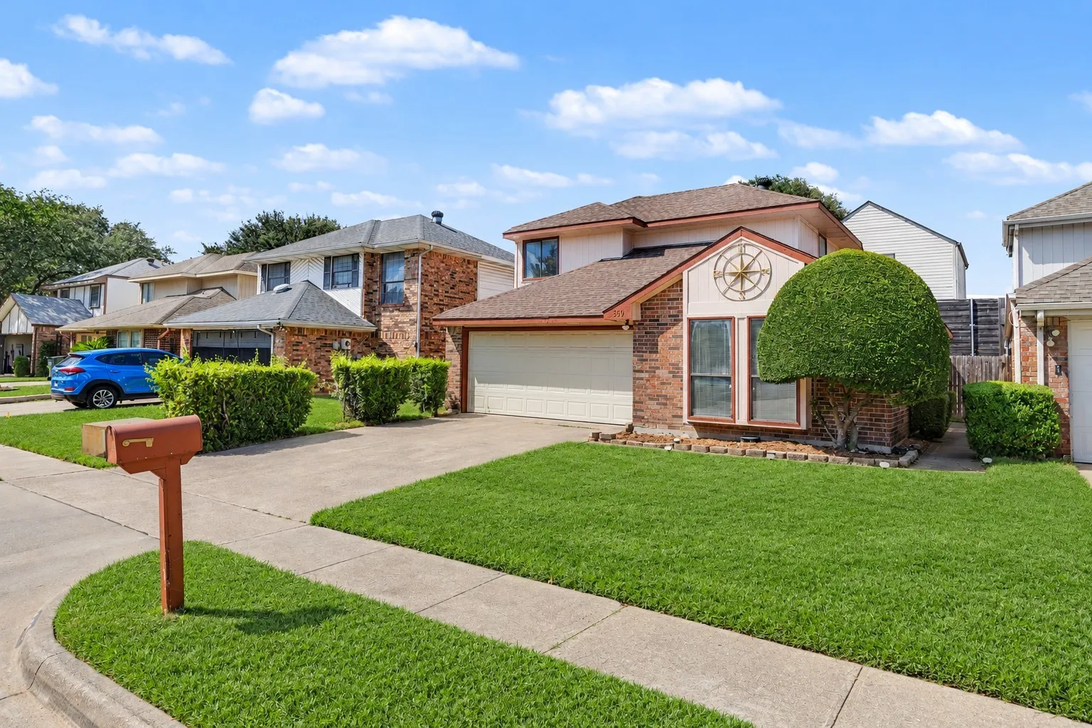 Brick facade residence featuring an attached garage, concrete driveway, and front lawn