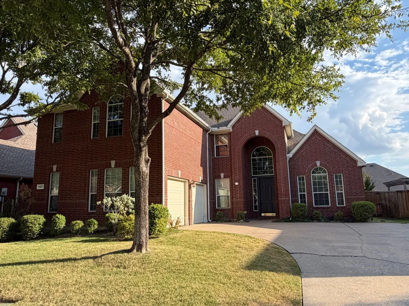 Brick exterior with arched entry, arched windows, dual garage doors, and a concrete driveway