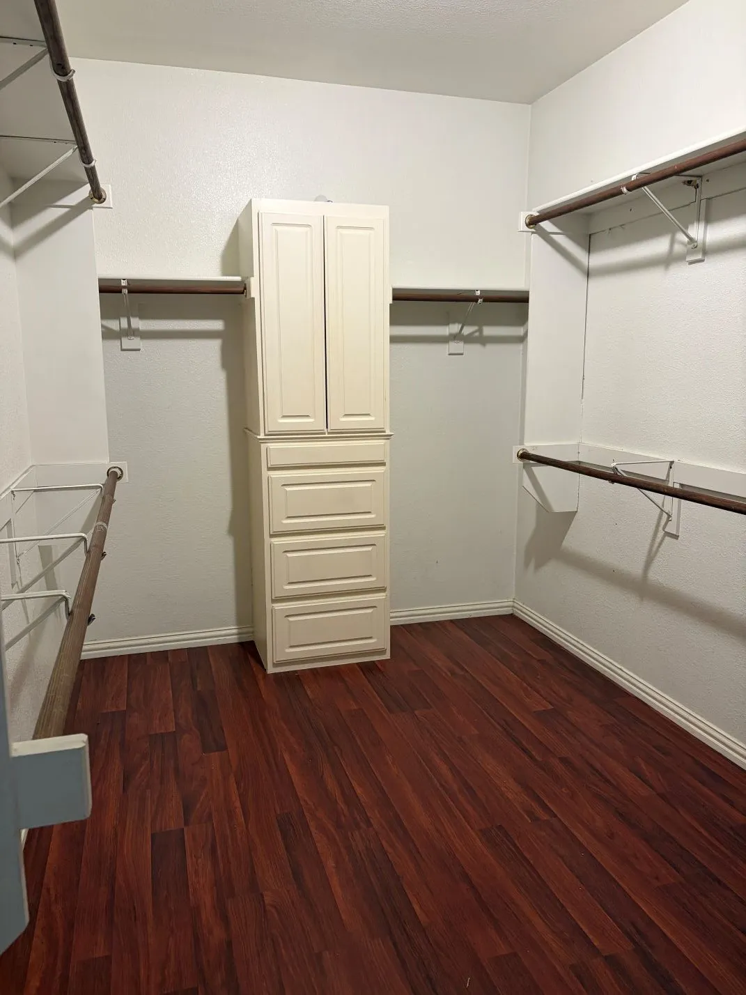 Walk-in closet with wood-finish flooring, built-in cabinetry, multiple hanging rods, and shelving