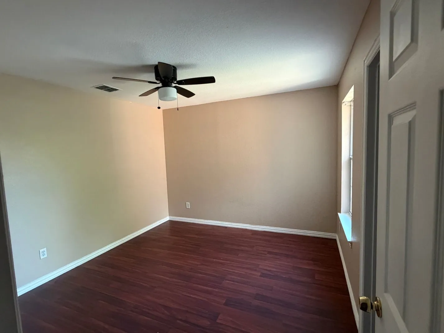 Room featuring wood-finish flooring, neutral wall tones, a ceiling fan with integrated lighting, and a white-trimmed window