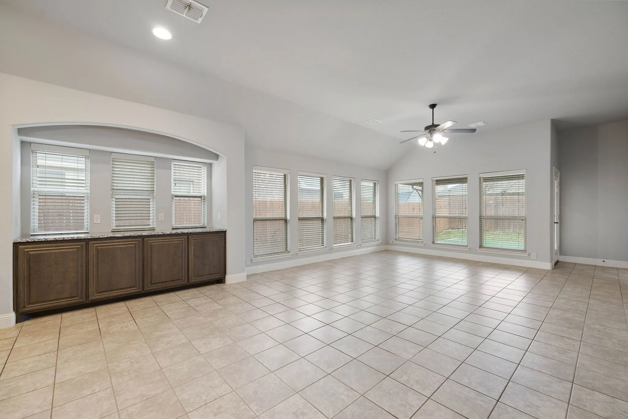 Unfurnished room featuring light tile patterned floors, vaulted ceiling, and ceiling fan