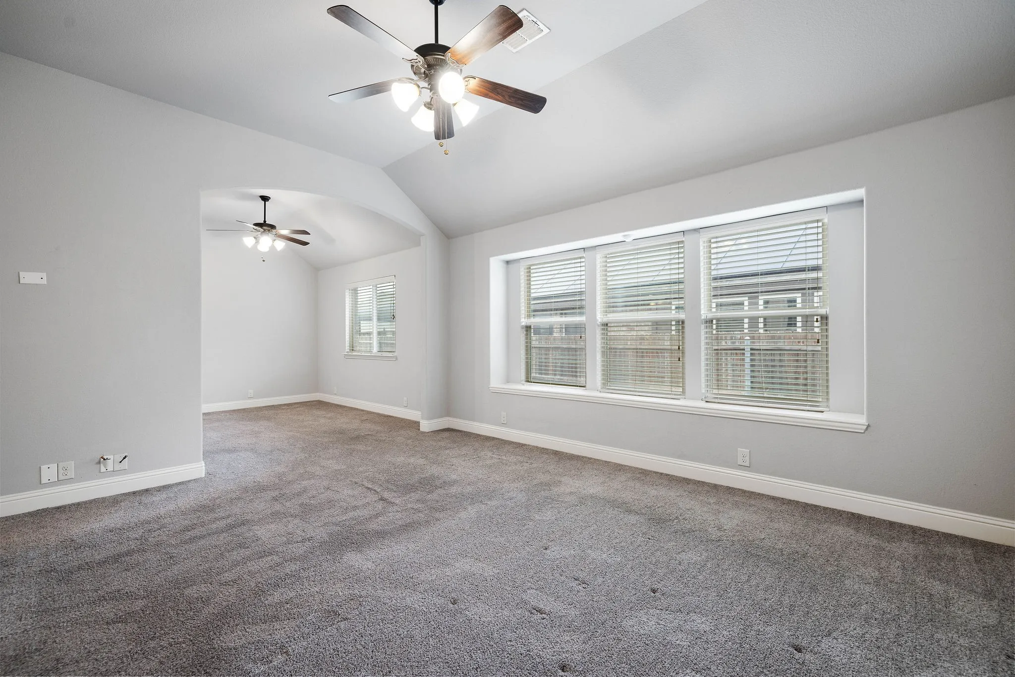 Primary bedroom featuring ceiling fan, lofted ceiling, and carpet flooring