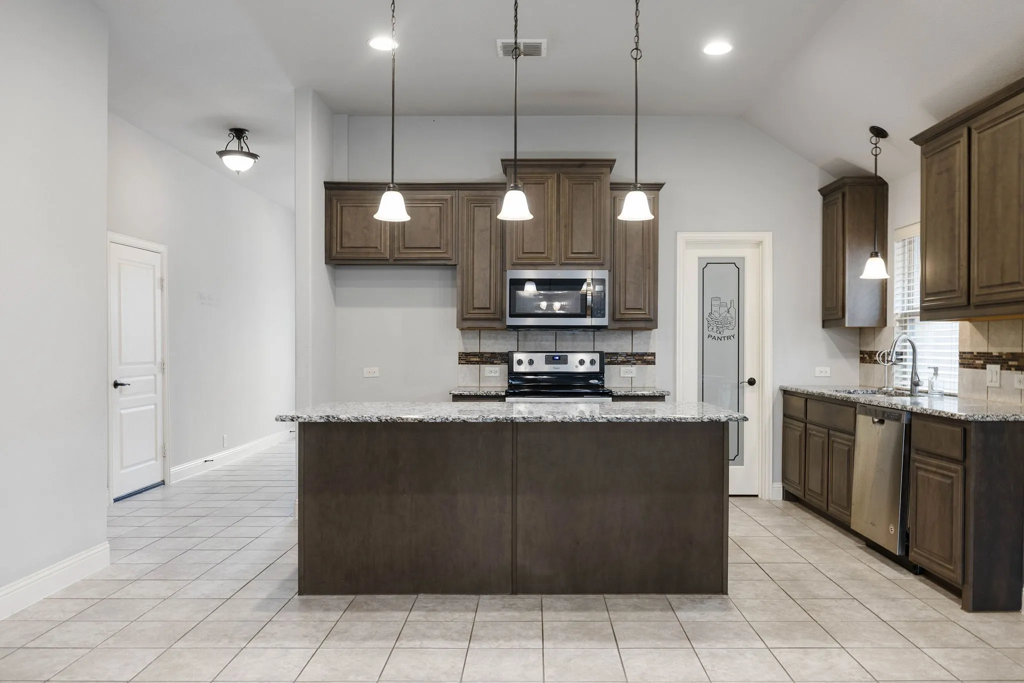 Kitchen with appliances with stainless steel finishes, a center island, sink, and light stone counters