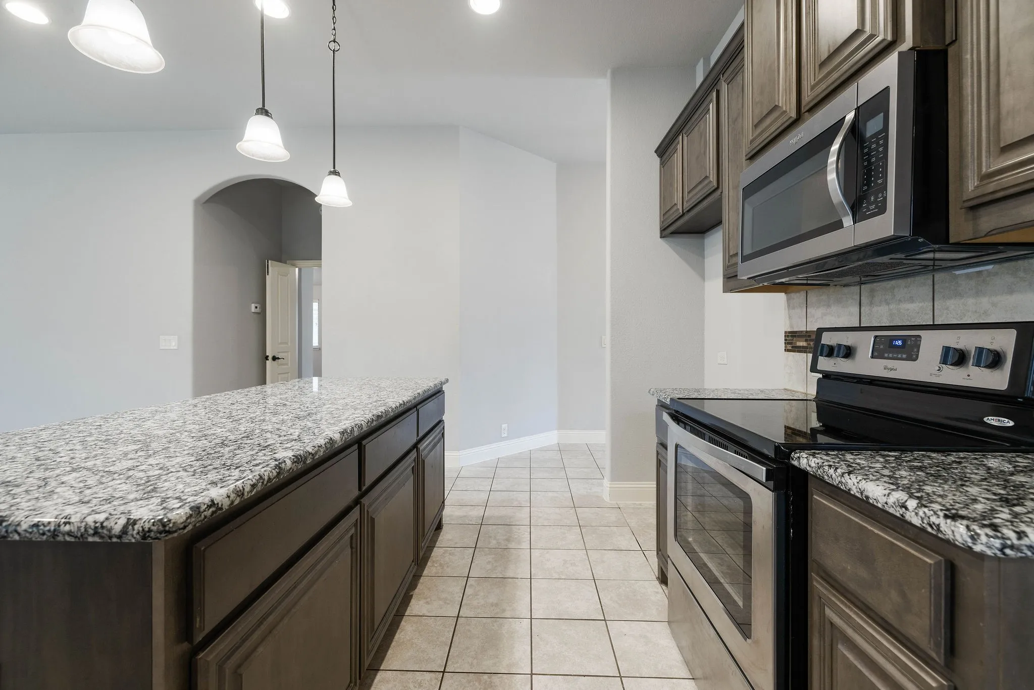Kitchen featuring stainless steel appliances, dark brown cabinets, pendant lighting, and decorative backsplash