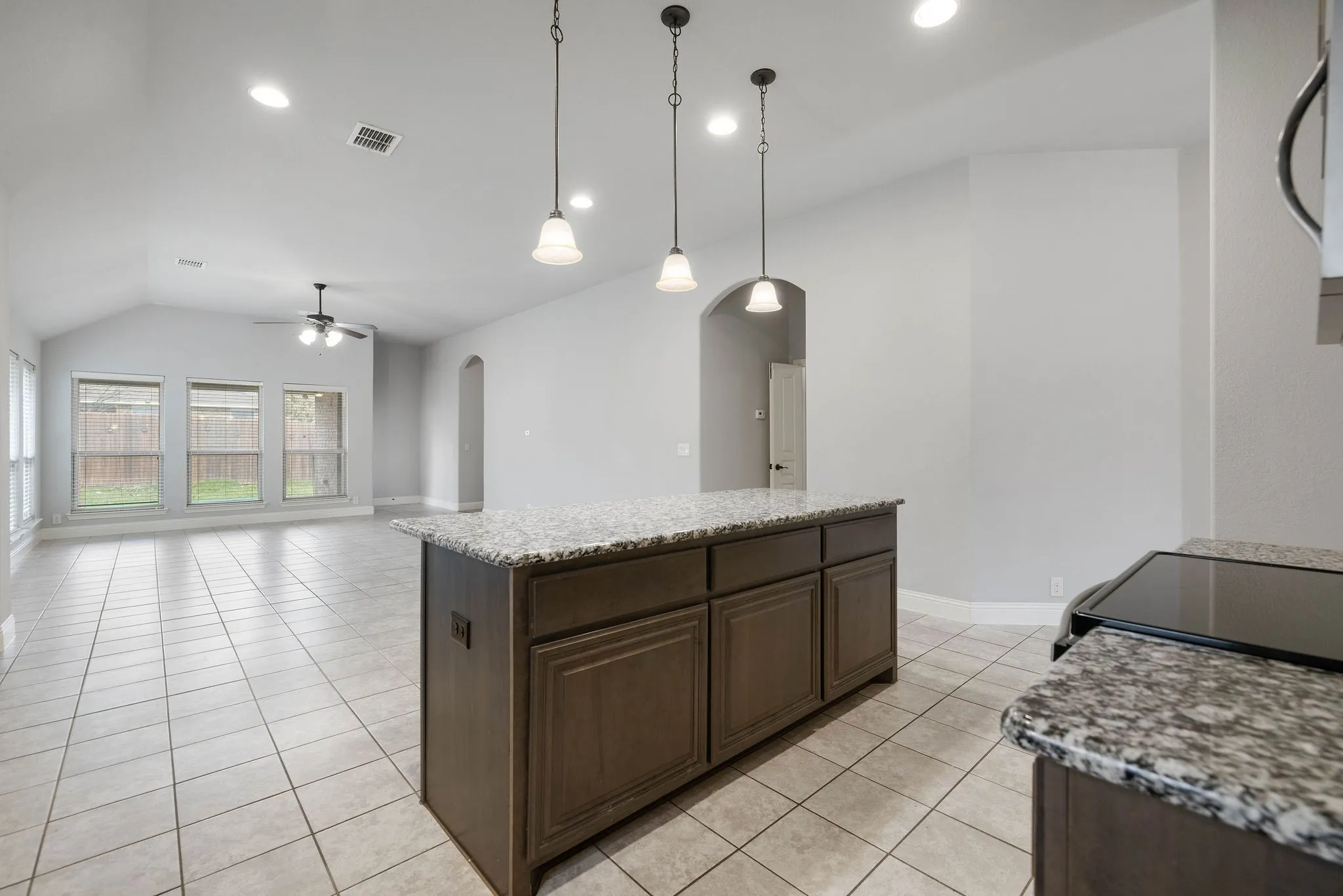 Kitchen with light tile patterned flooring, a center island, vaulted ceiling, hanging light fixtures, and ceiling fan