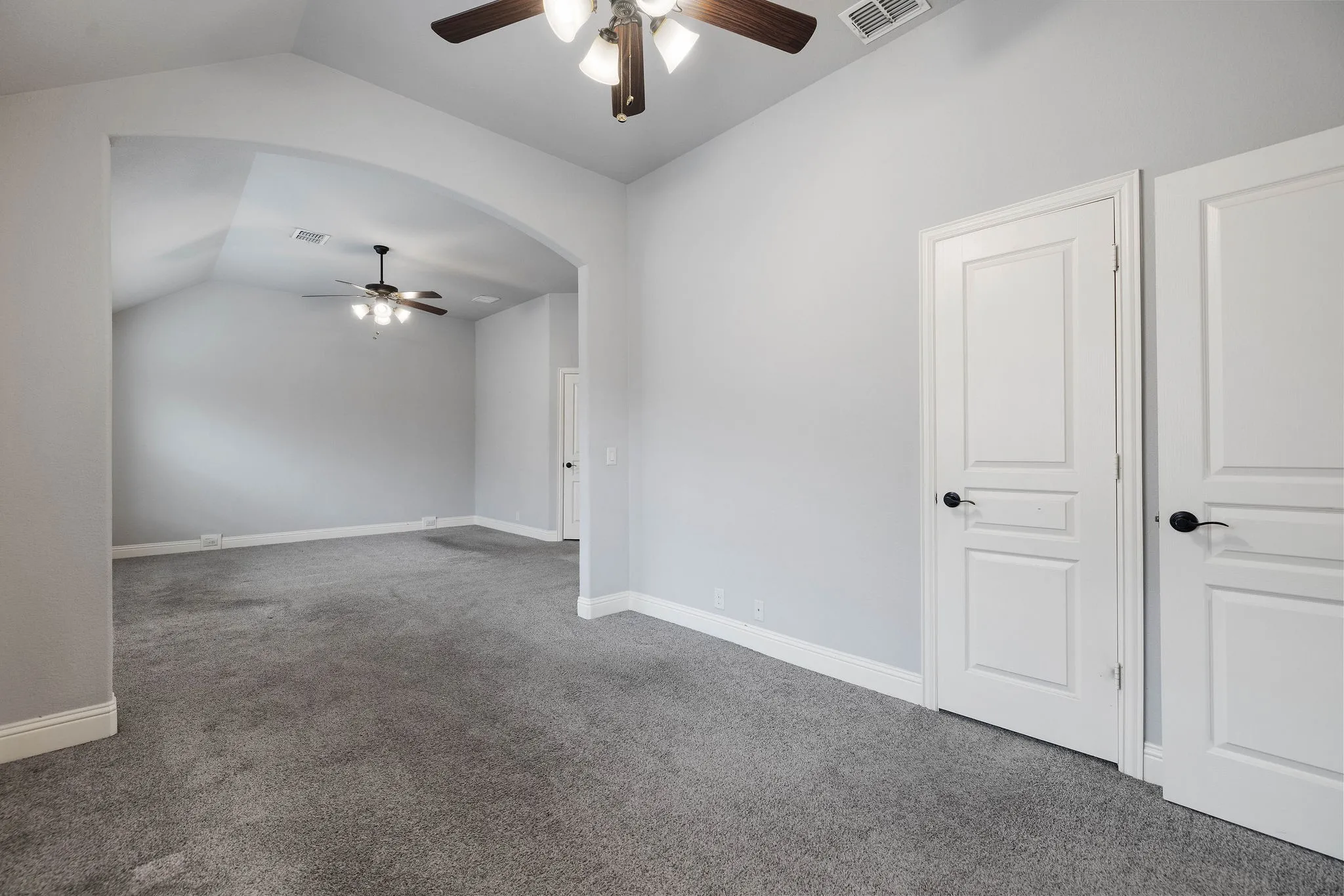 Carpeted spare area in primary bedroom with vaulted ceiling and ceiling fan