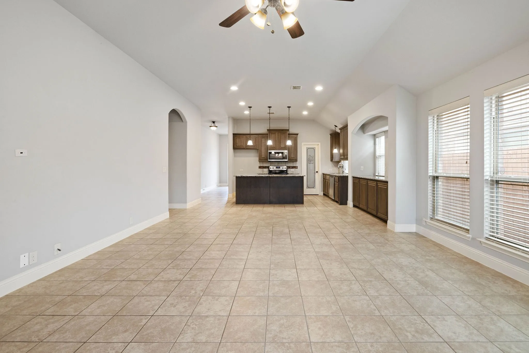Kitchen featuring light tile patterned flooring, vaulted ceiling, hanging light fixtures, a kitchen island, and ceiling fan