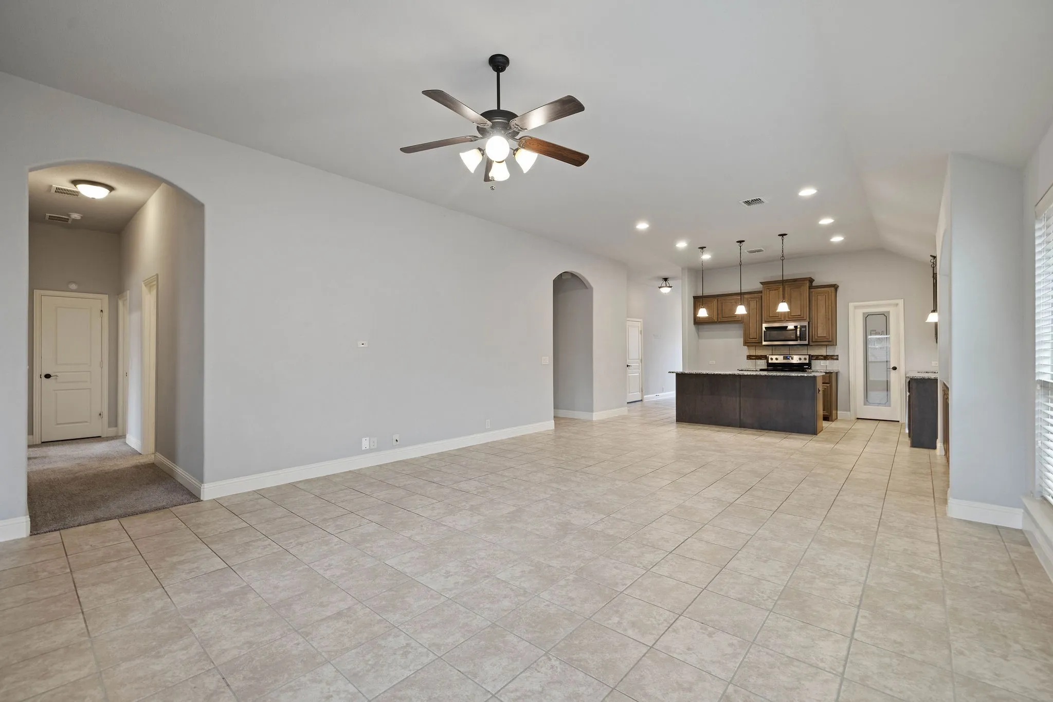 Open concept living room featuring lofted ceiling, light tile patterned floors, and ceiling fan
