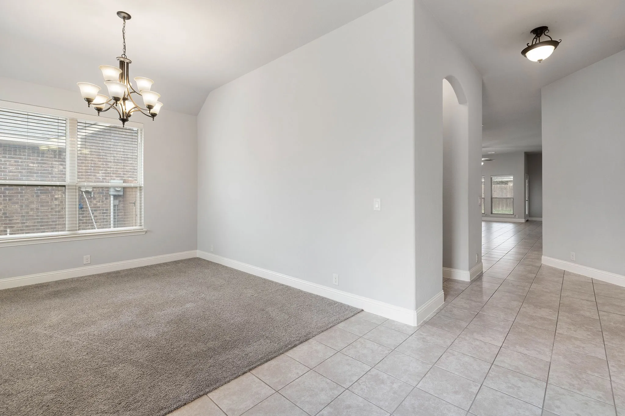 Carpeted flex room featuring lofted ceiling and a notable chandelier