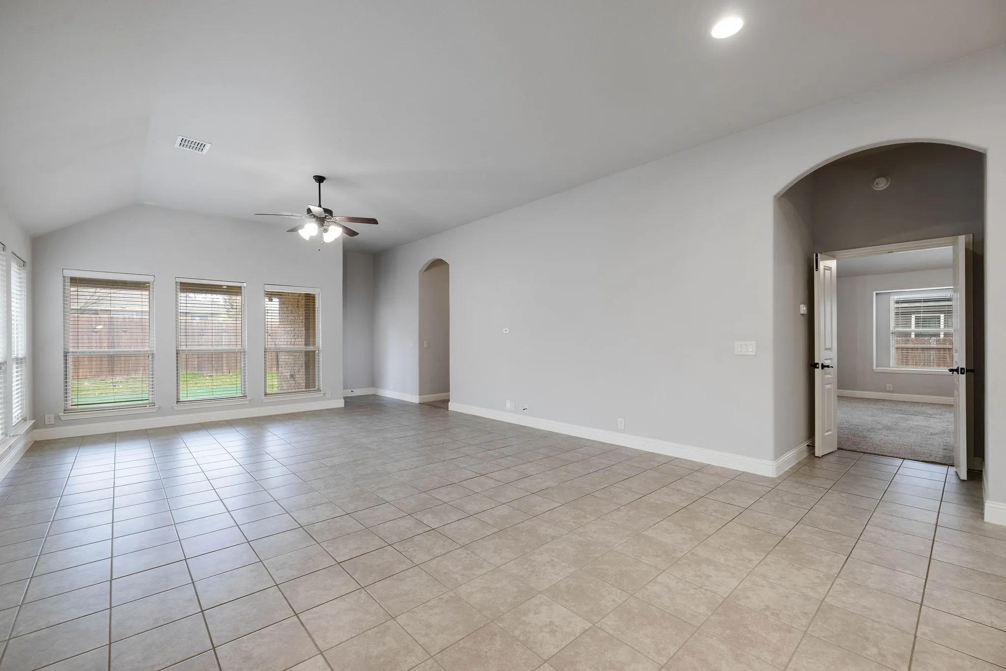 Spare room with light tile patterned floors, a wealth of natural light, and ceiling fan