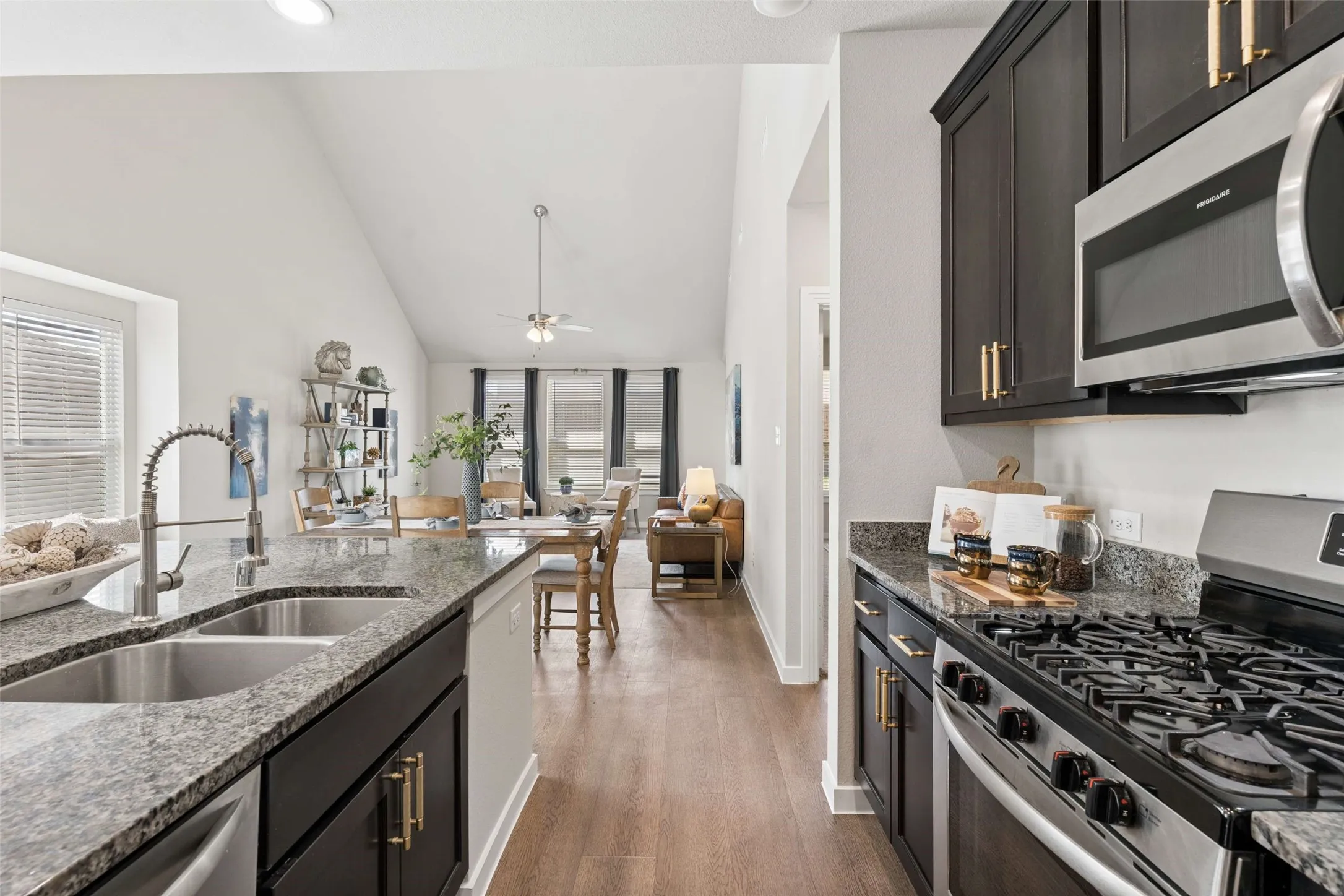 Kitchen featuring granite countertops, dark wood-finish cabinetry, stainless steel appliances, and a dual basin sink
