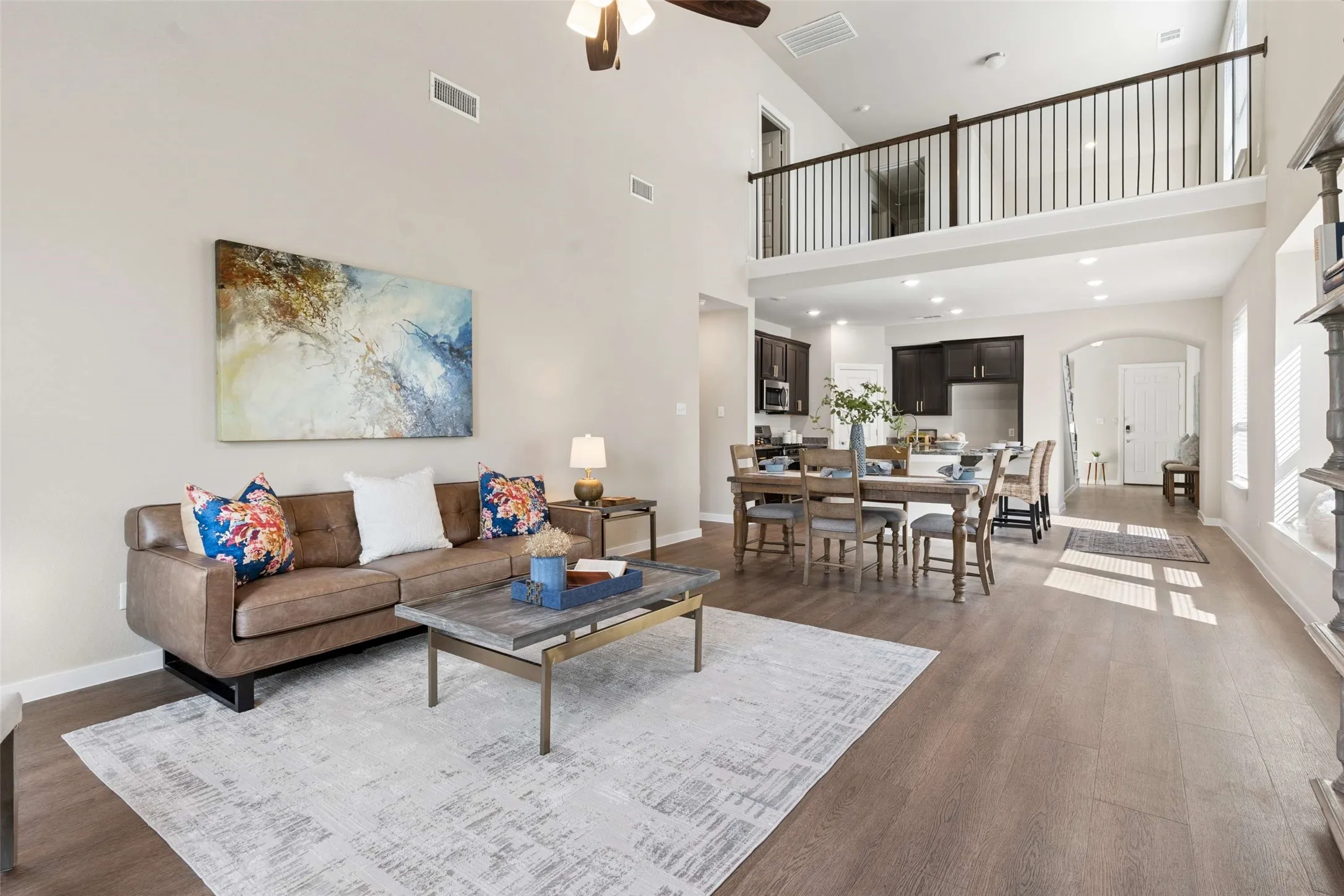 Open concept living area featuring wood-finish flooring, vaulted ceilings, and a second-story interior balcony with dark wood railing