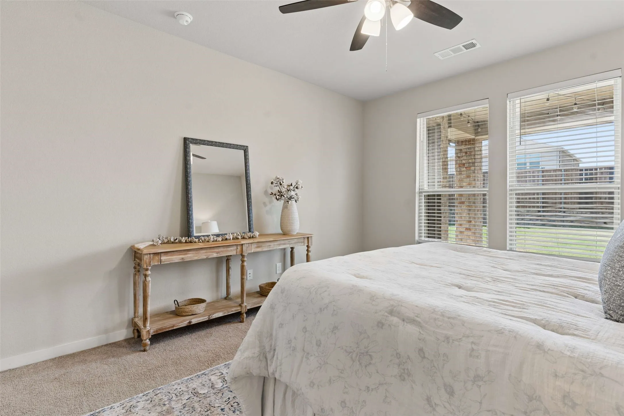 Light-toned walls, neutral carpet, and a ceiling fan with integrated lighting