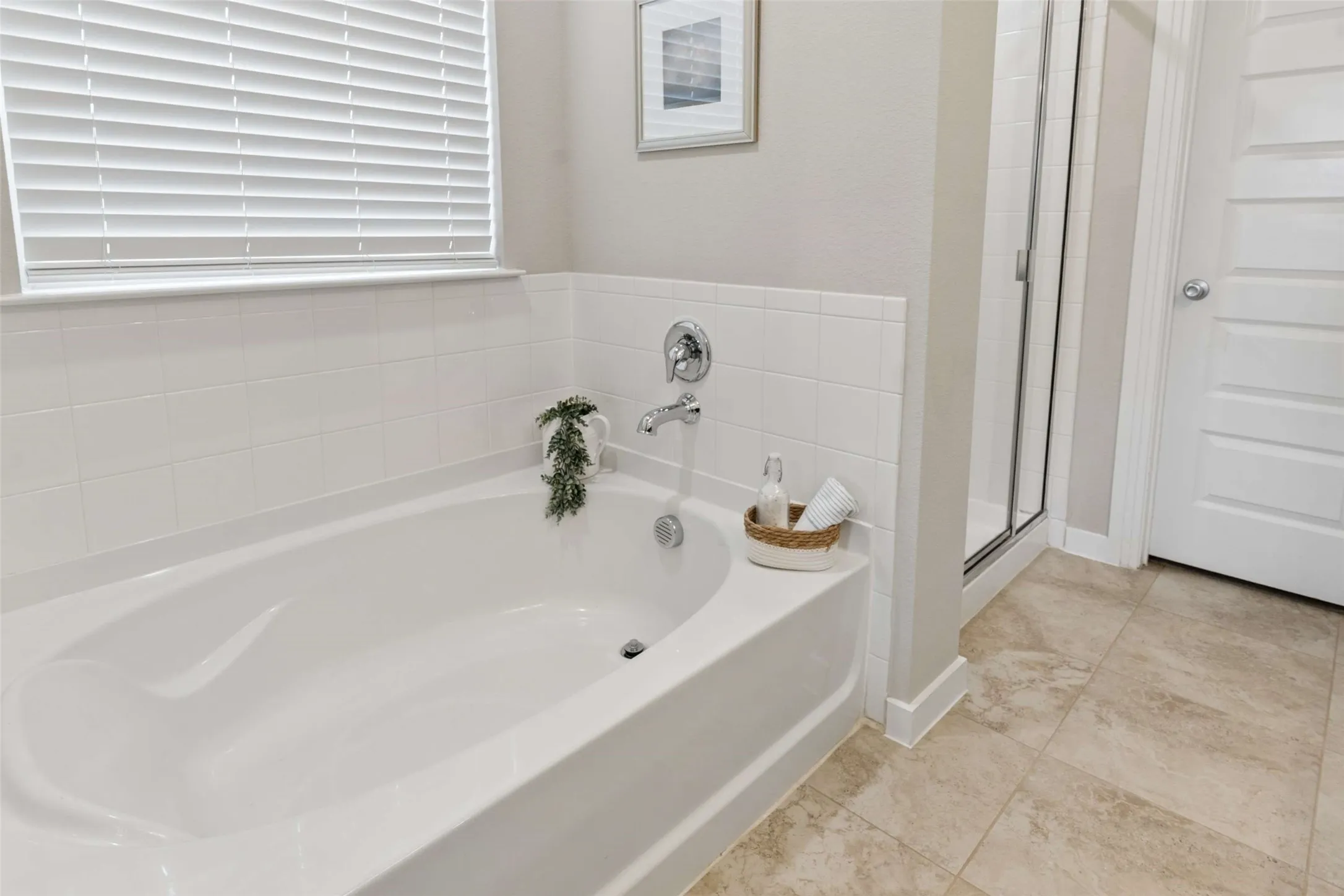 White soaking tub with chrome fixtures, white subway tile surround, tiled flooring, and a glass-enclosed shower
