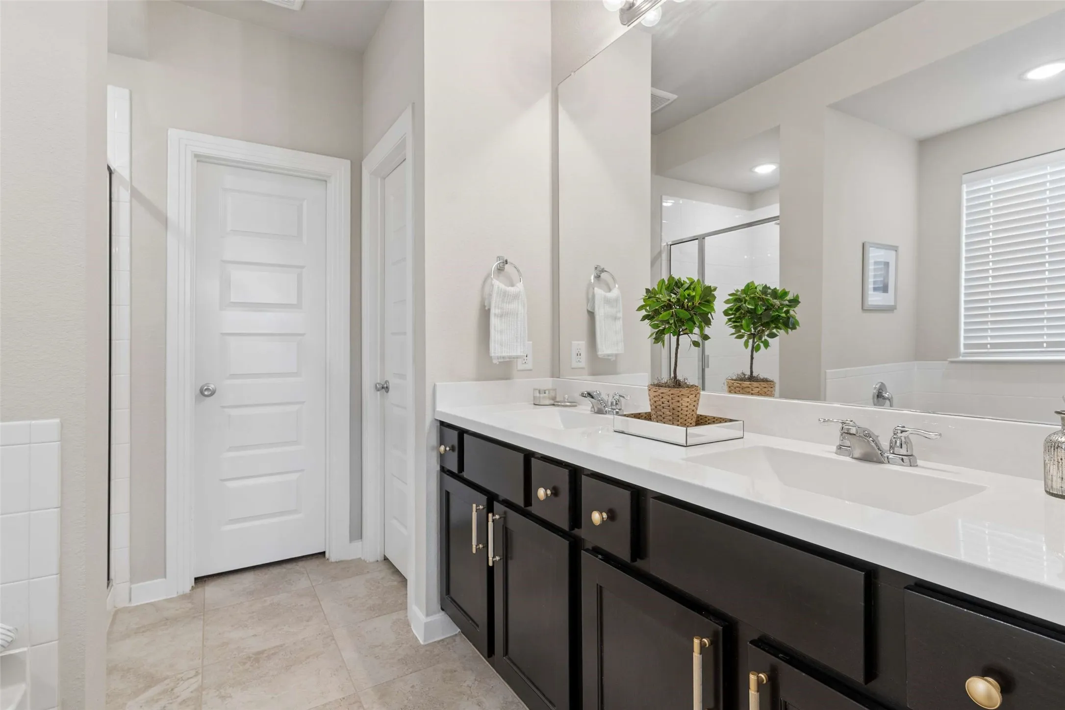 Dual vanity with dark wood cabinetry, white countertops, and chrome fixtures
