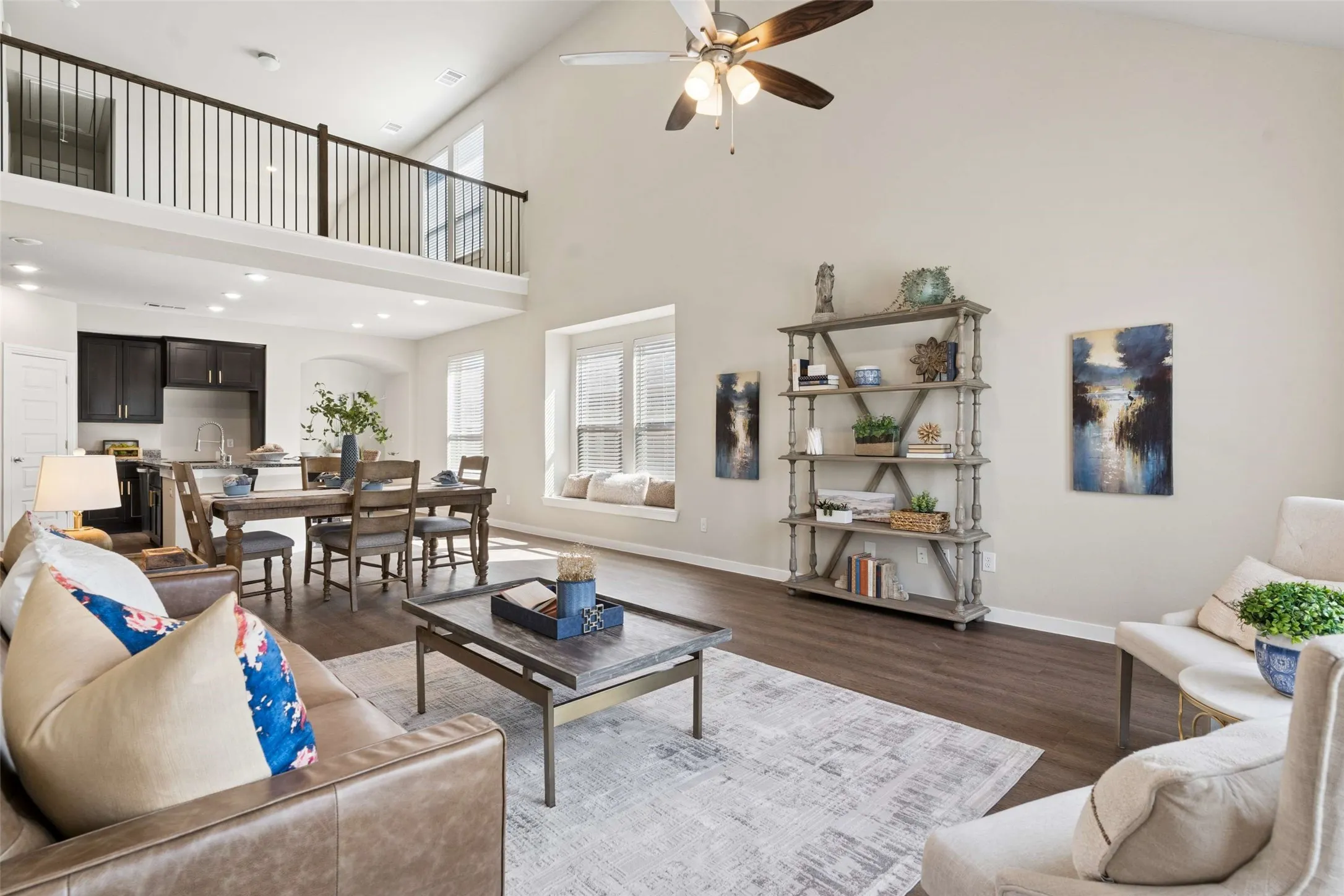 Vaulted ceilings with a ceiling fan, wood-finish flooring, built-in window seating, dark wood cabinetry, and an open concept layout