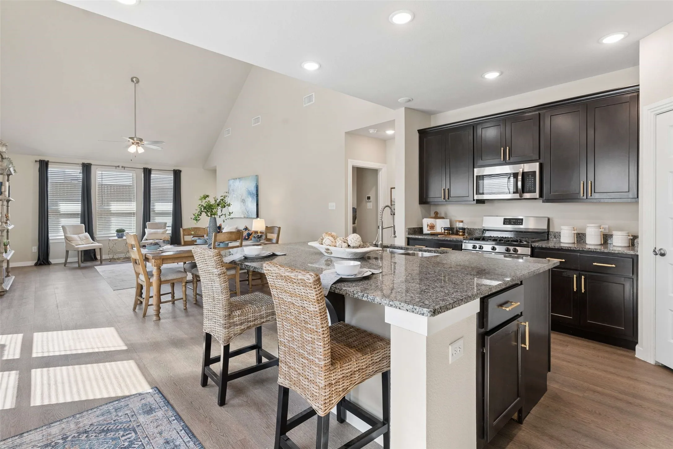 Kitchen with dark wood-finish cabinetry, stainless steel appliances, and a granite-topped island
