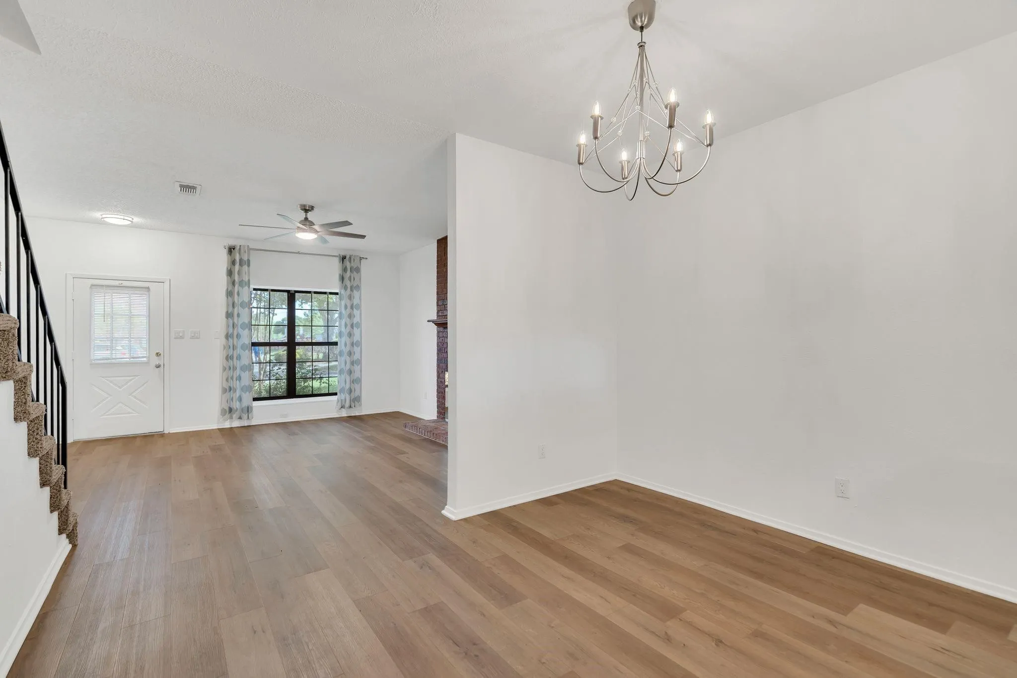 Wood-finish flooring throughout, bright white walls, and a multi-pane window with a light-colored window treatment