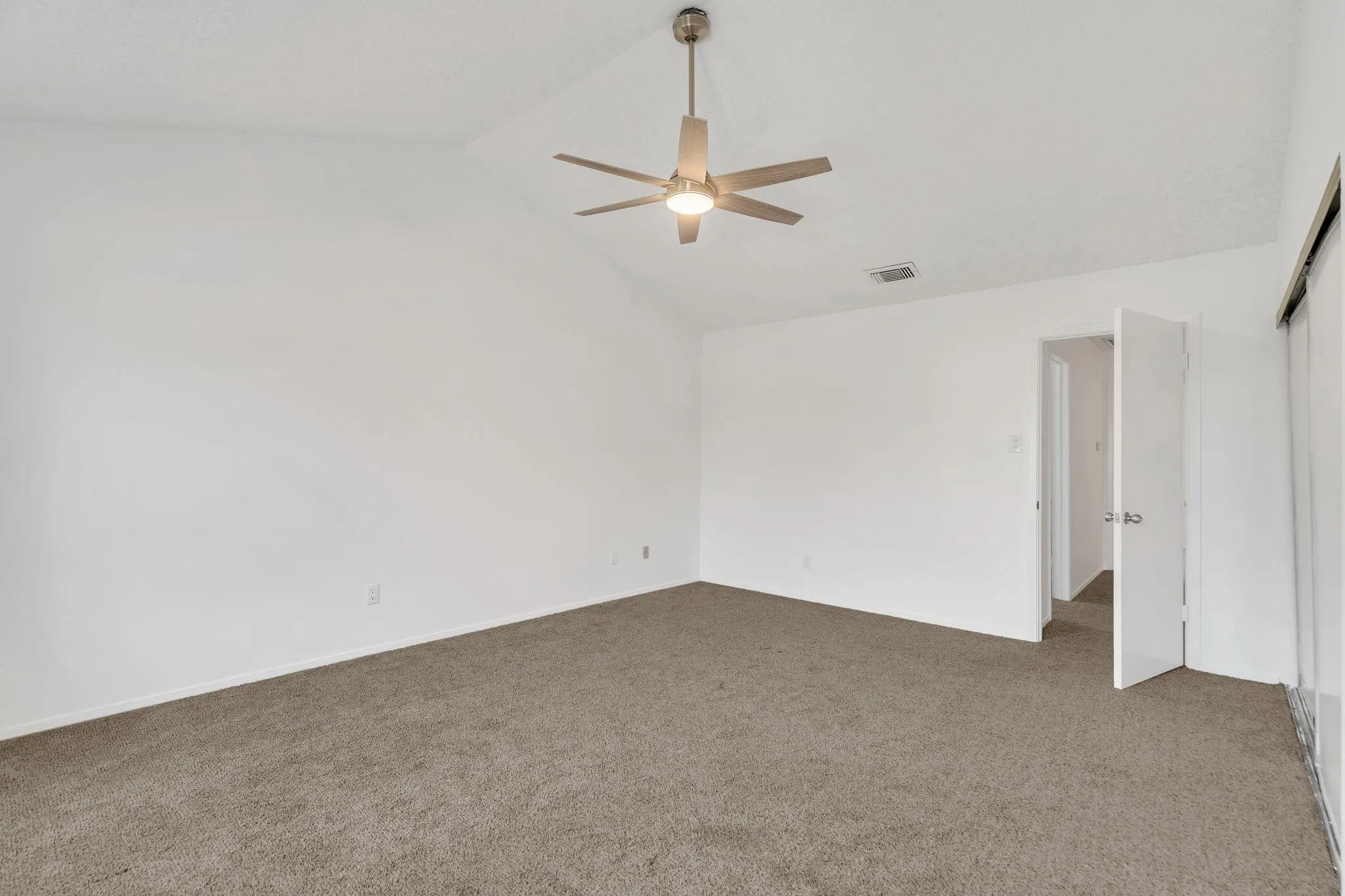 Vaulted ceiling, ceiling fan with integrated lighting, neutral carpet flooring, and white wall finishes