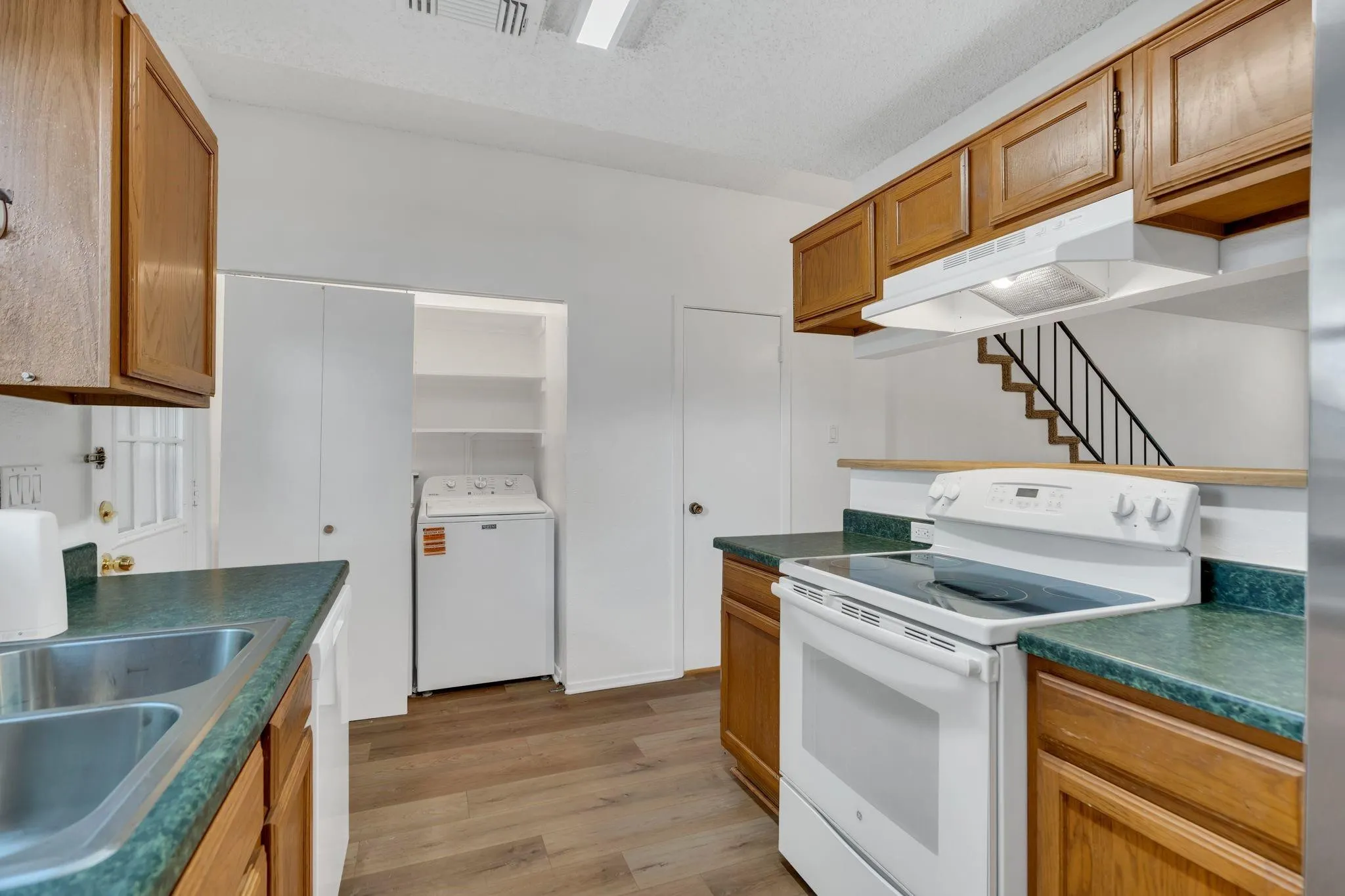 Kitchen featuring wood-finish cabinetry, built-in range, dual basin sink, and wood-finish flooring