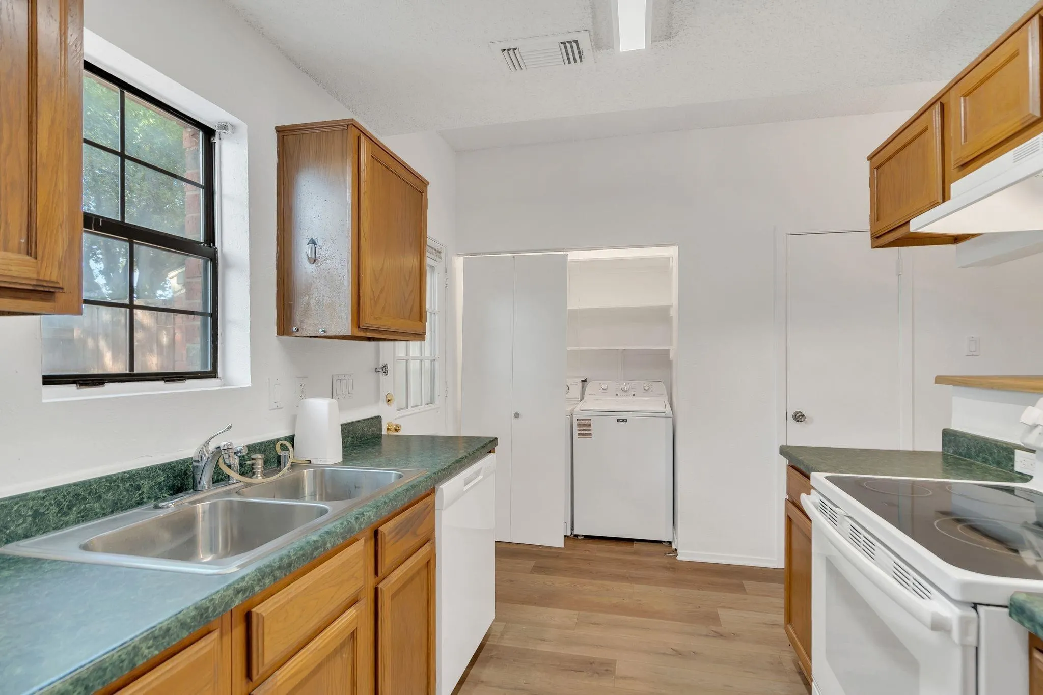 Kitchen featuring wood-finish cabinetry, a double basin stainless steel sink, and a built-in electric range