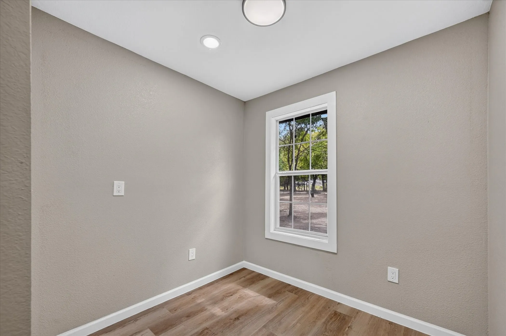 Recessed ceiling lighting, wood-finish flooring, and a window with white trim