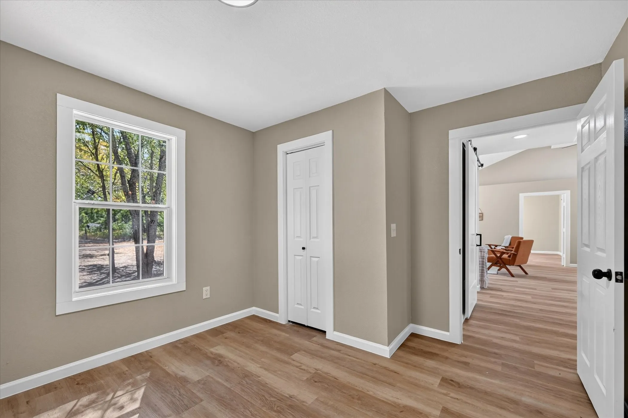 Wood-finish flooring throughout, white trim, recessed lighting, and a white paneled bi-fold closet door