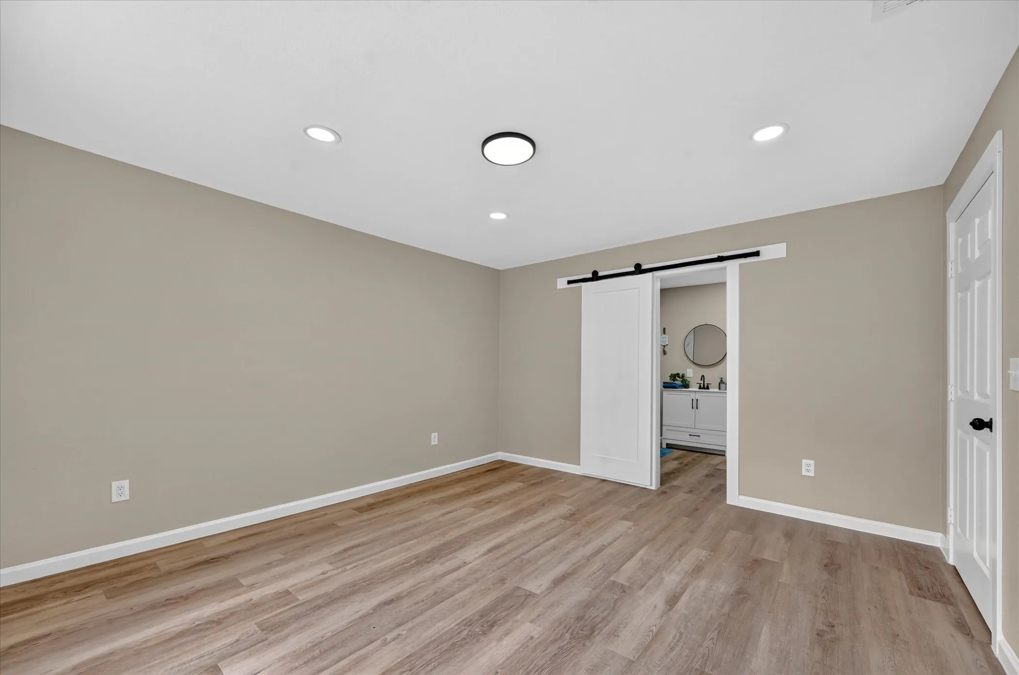 Recessed lighting, flush-mount ceiling light, wood-finish flooring, neutral wall tones, and a sliding barn door