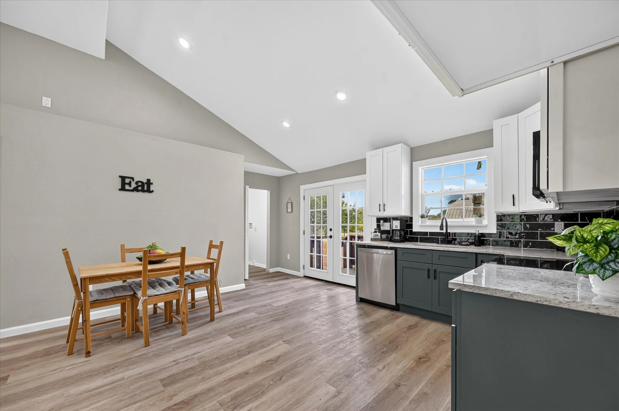 Kitchen with wood-finish flooring, two-tone cabinetry, stainless steel appliances, a subway tile backsplash, and French doors