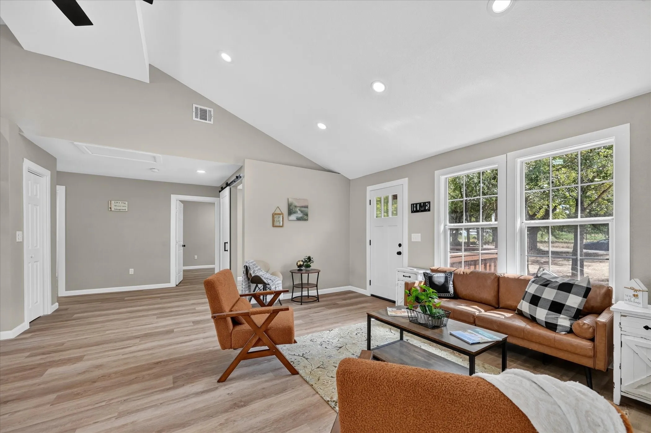 Vaulted ceilings with recessed lighting, wood-finish flooring, white trim, and a white paneled front door with glass inserts