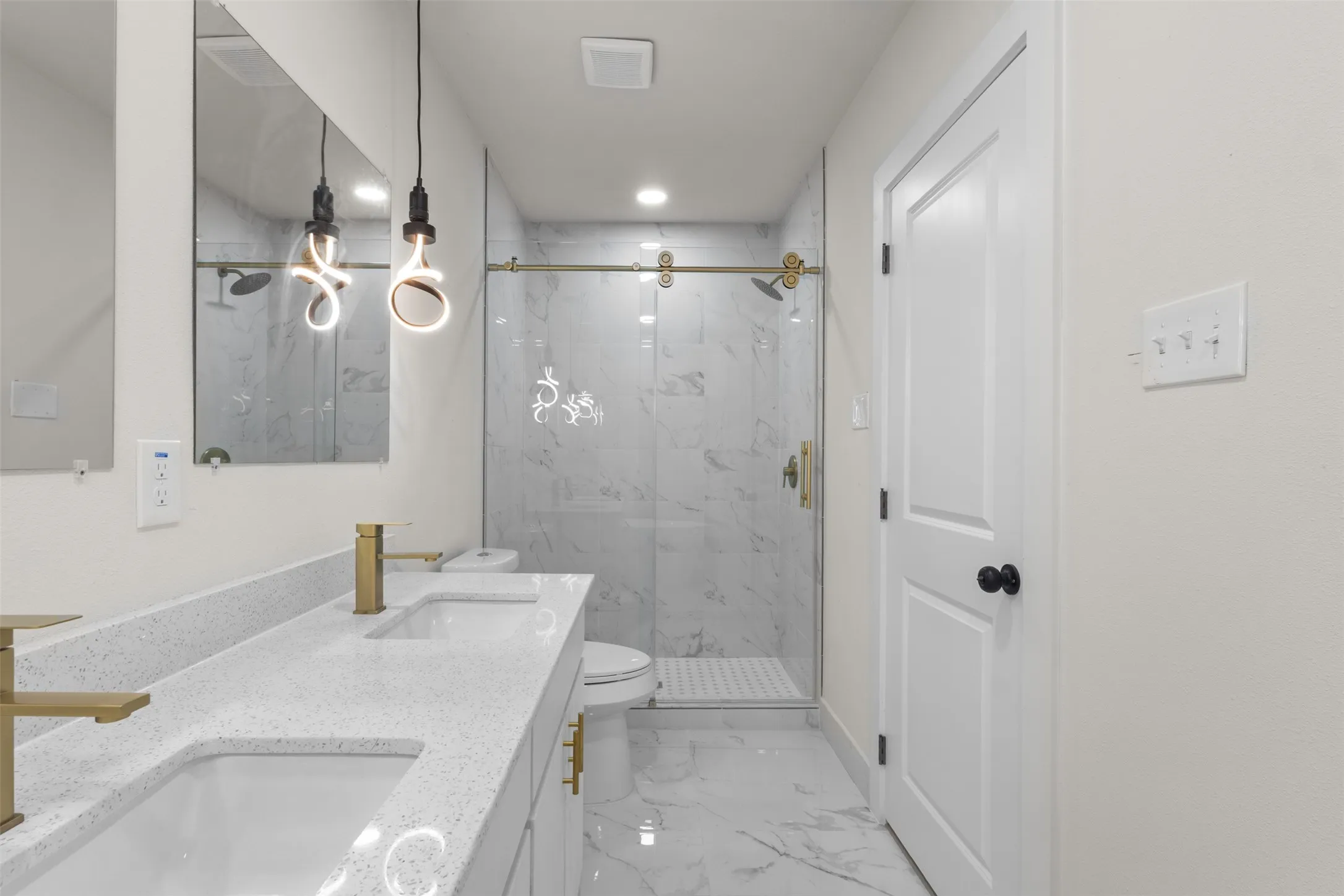 Dual vanity with gold-finish fixtures and white speckled countertops
