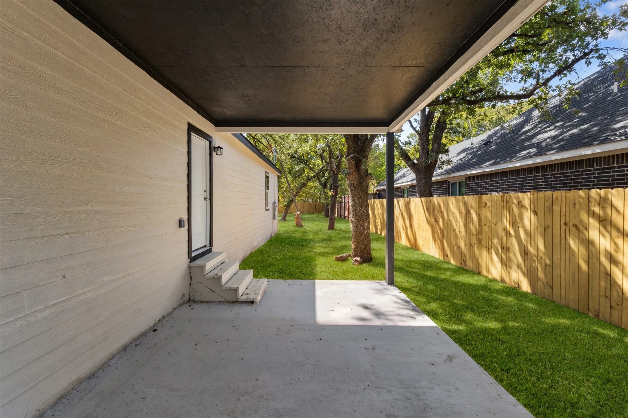 Covered concrete patio with direct outdoor access and a spacious grassy yard