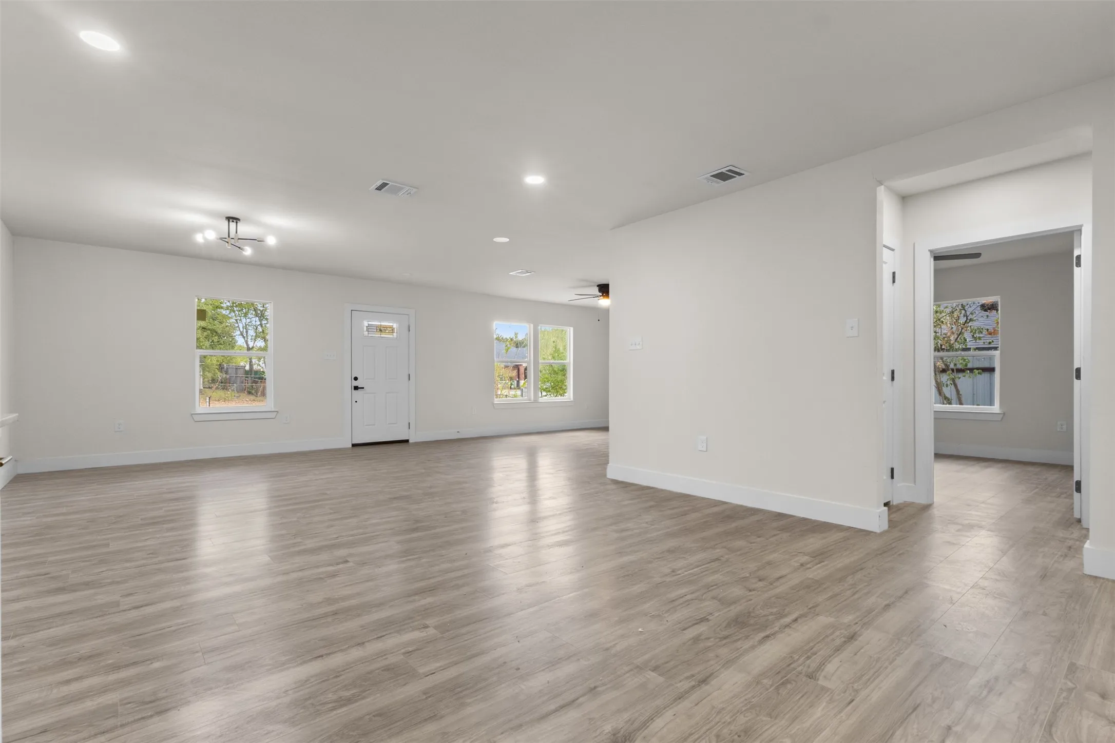 Expansive room with wood-finish flooring, recessed lighting, and a contemporary ceiling fixture