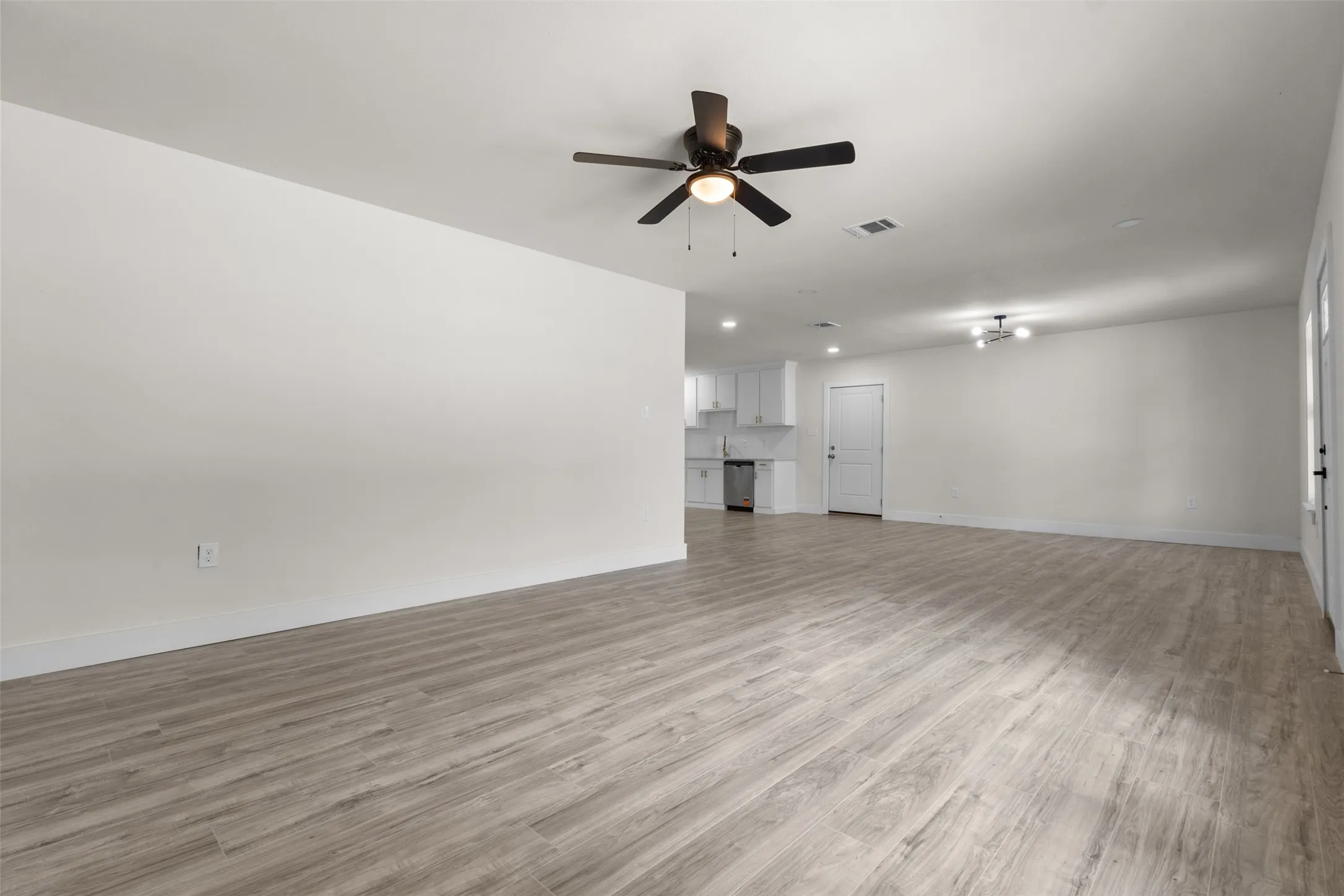 Open-concept living area featuring wood-finish flooring, recessed lighting, ceiling fans, and a neutral color palette