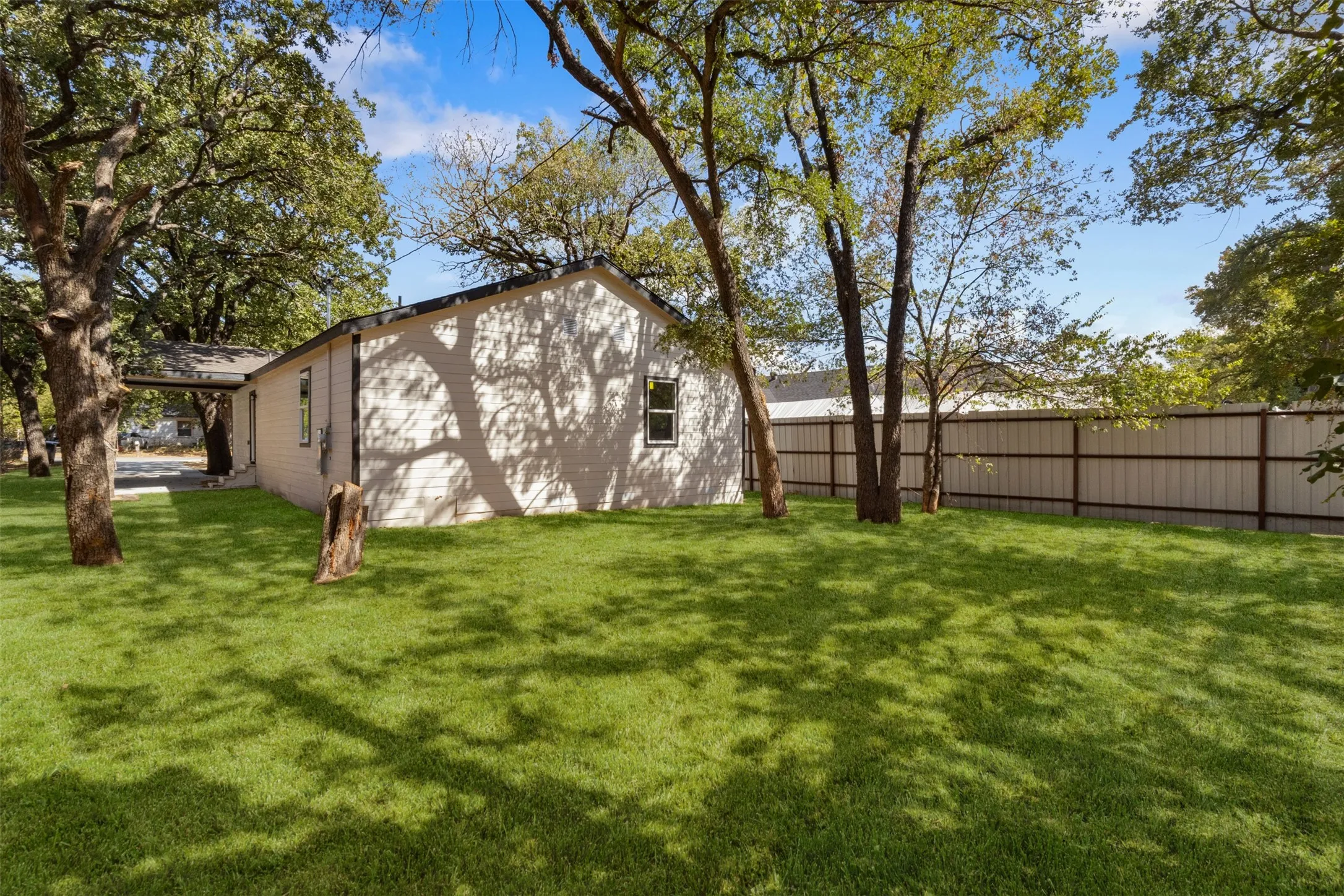Expansive lawn with mature trees and a privacy fence