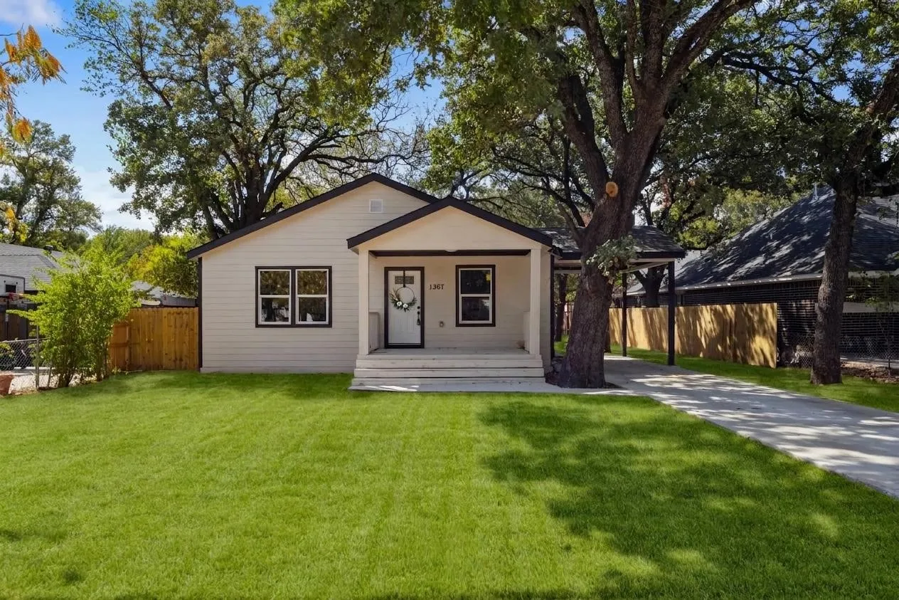 Light-colored siding home with a covered front porch, dark-framed windows, a driveway, and a covered carport