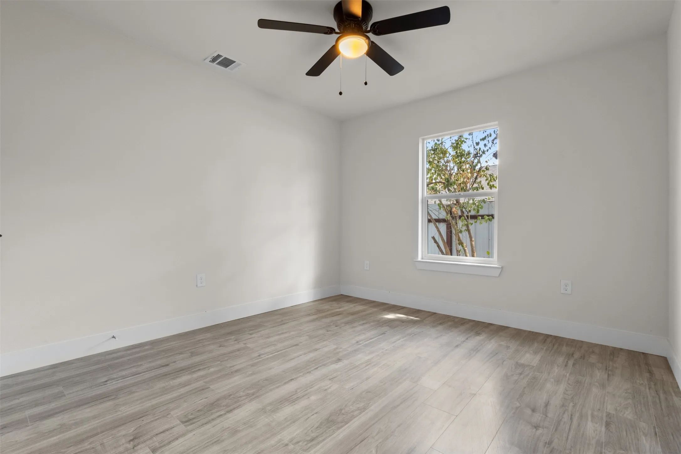 Wood-finish flooring, single window, and a ceiling fan with integrated lighting