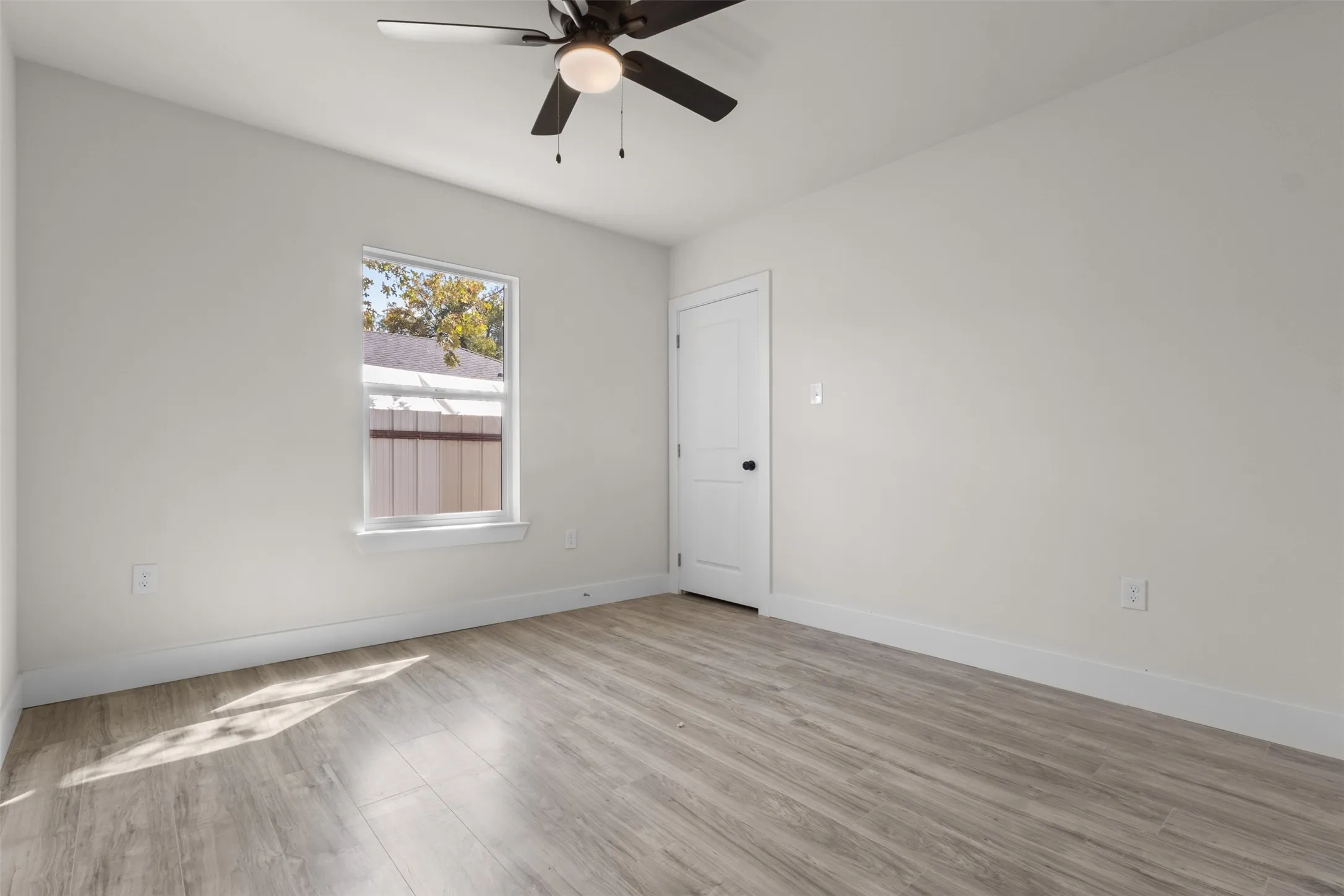Bright room featuring wood-finish flooring and a ceiling fan